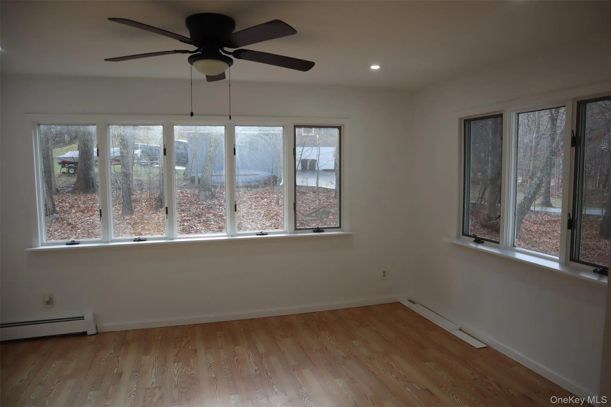 Empty room with light wood-style flooring, recessed lighting, a ceiling fan, and a baseboard heating unit Empty room with light wood-style flooring, recessed lighting, a ceiling fan, and a baseboard heating unit