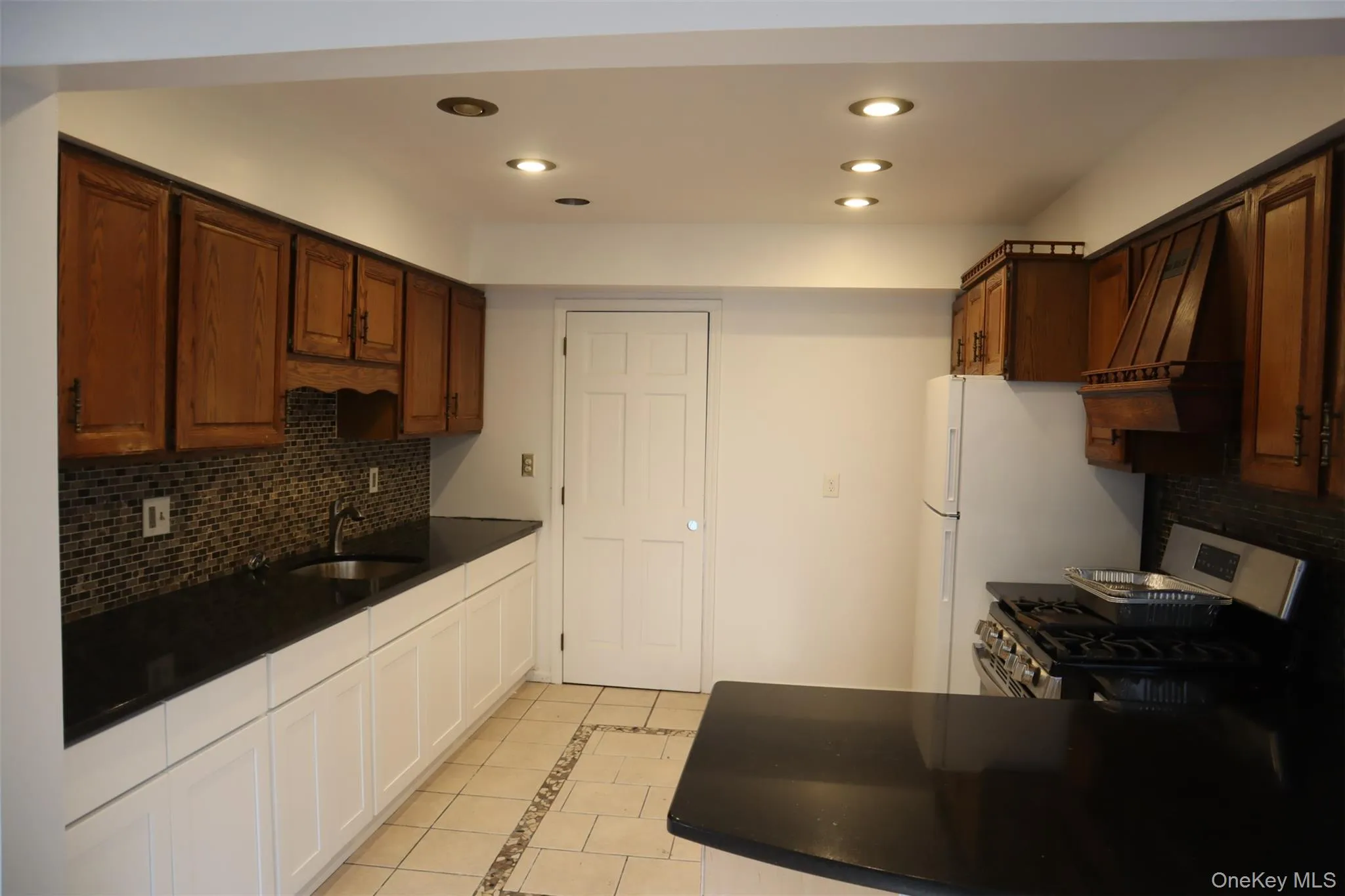 Kitchen featuring decorative backsplash, inlaid floor details, light tile patterned floors, custom range hood, and recessed lighting Kitchen featuring decorative backsplash, inlaid floor details, light tile patterned floors, custom range hood, and recessed lighting