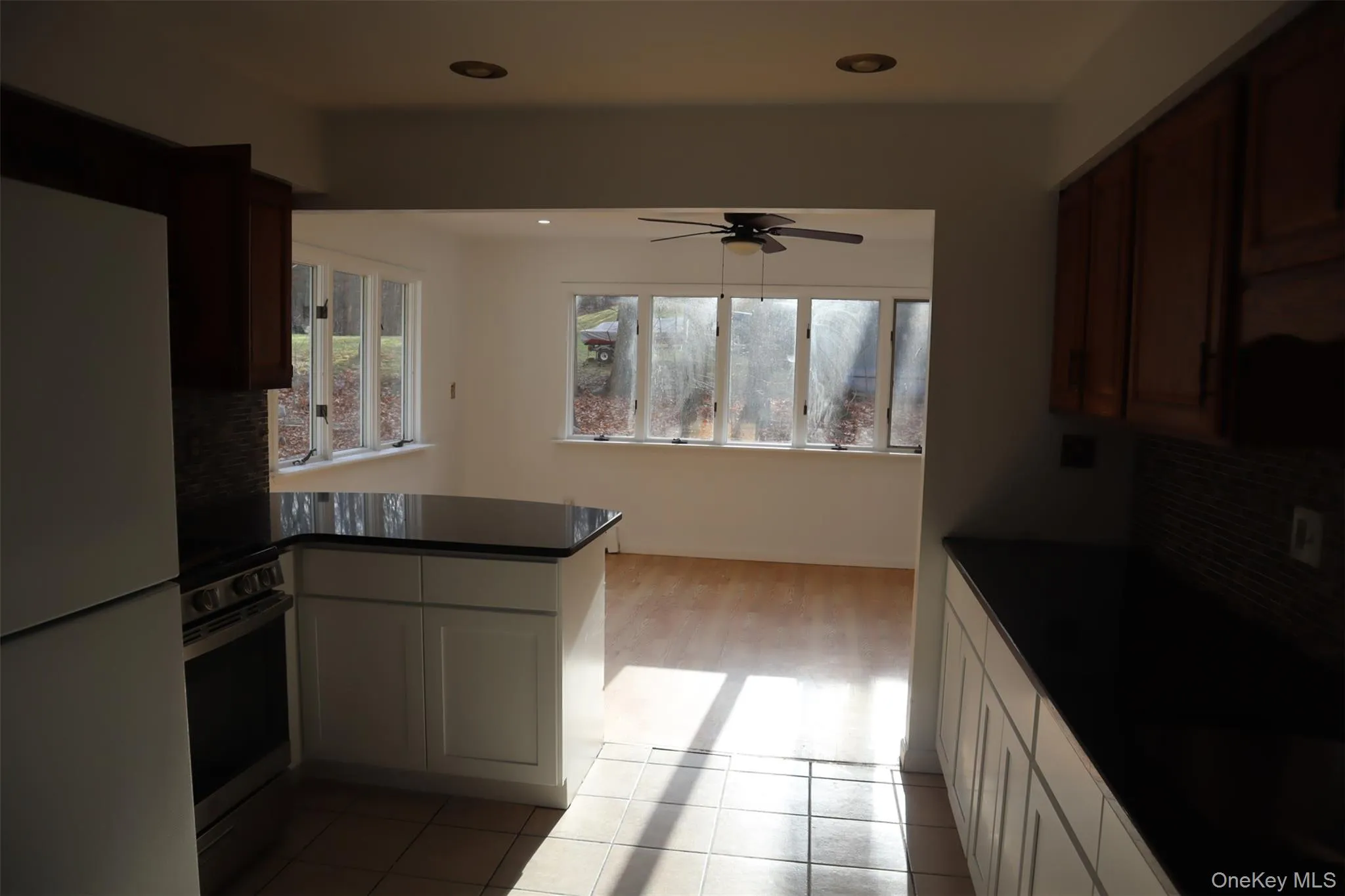 Kitchen featuring backsplash, freestanding refrigerator, a peninsula, stainless steel stove, and ceiling fan Kitchen featuring backsplash, freestanding refrigerator, a peninsula, stainless steel stove, and ceiling fan