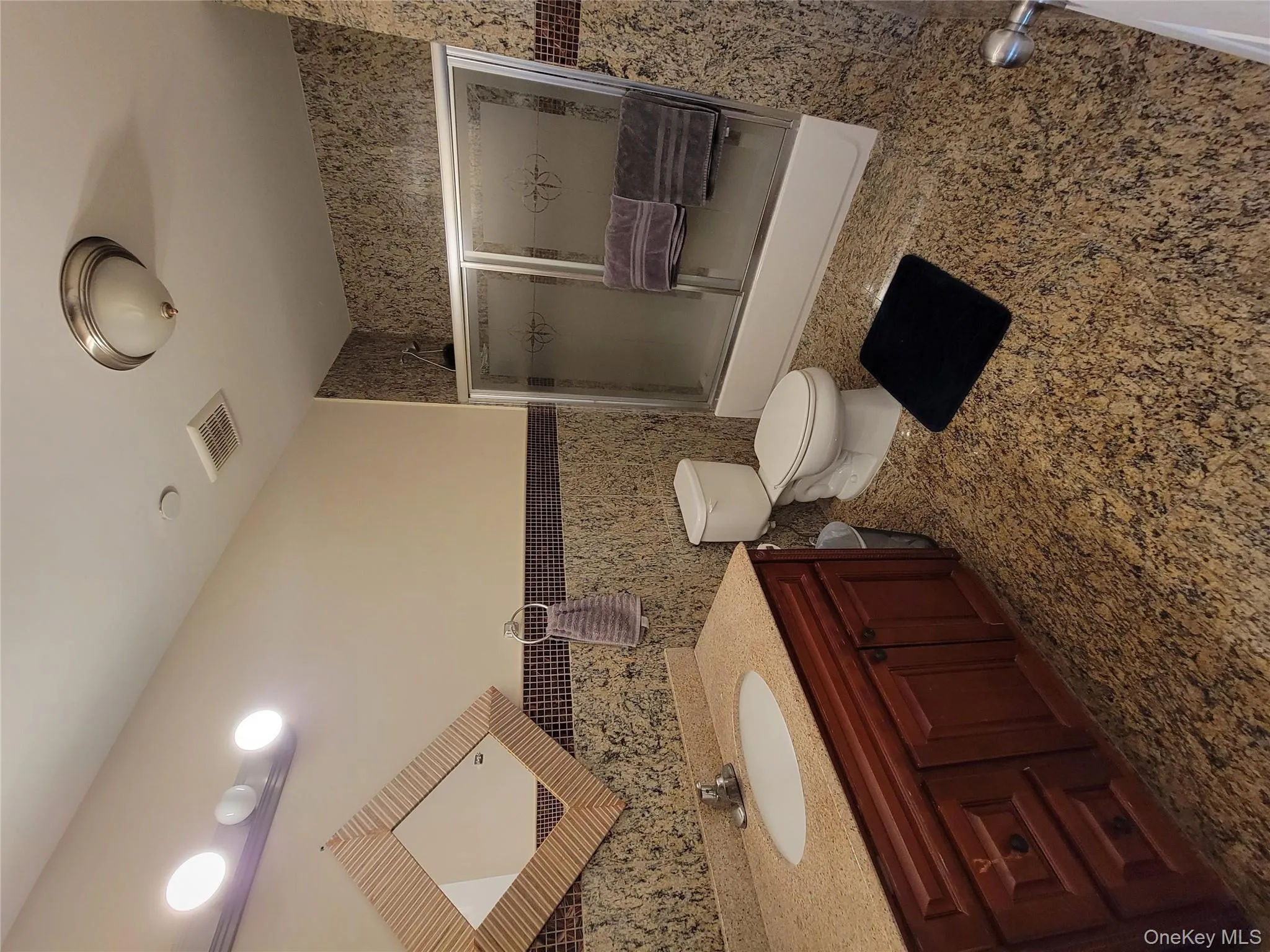 Bathroom featuring enclosed tub / shower combo, vanity, tile walls, and wainscoting Bathroom featuring enclosed tub / shower combo, vanity, tile walls, and wainscoting