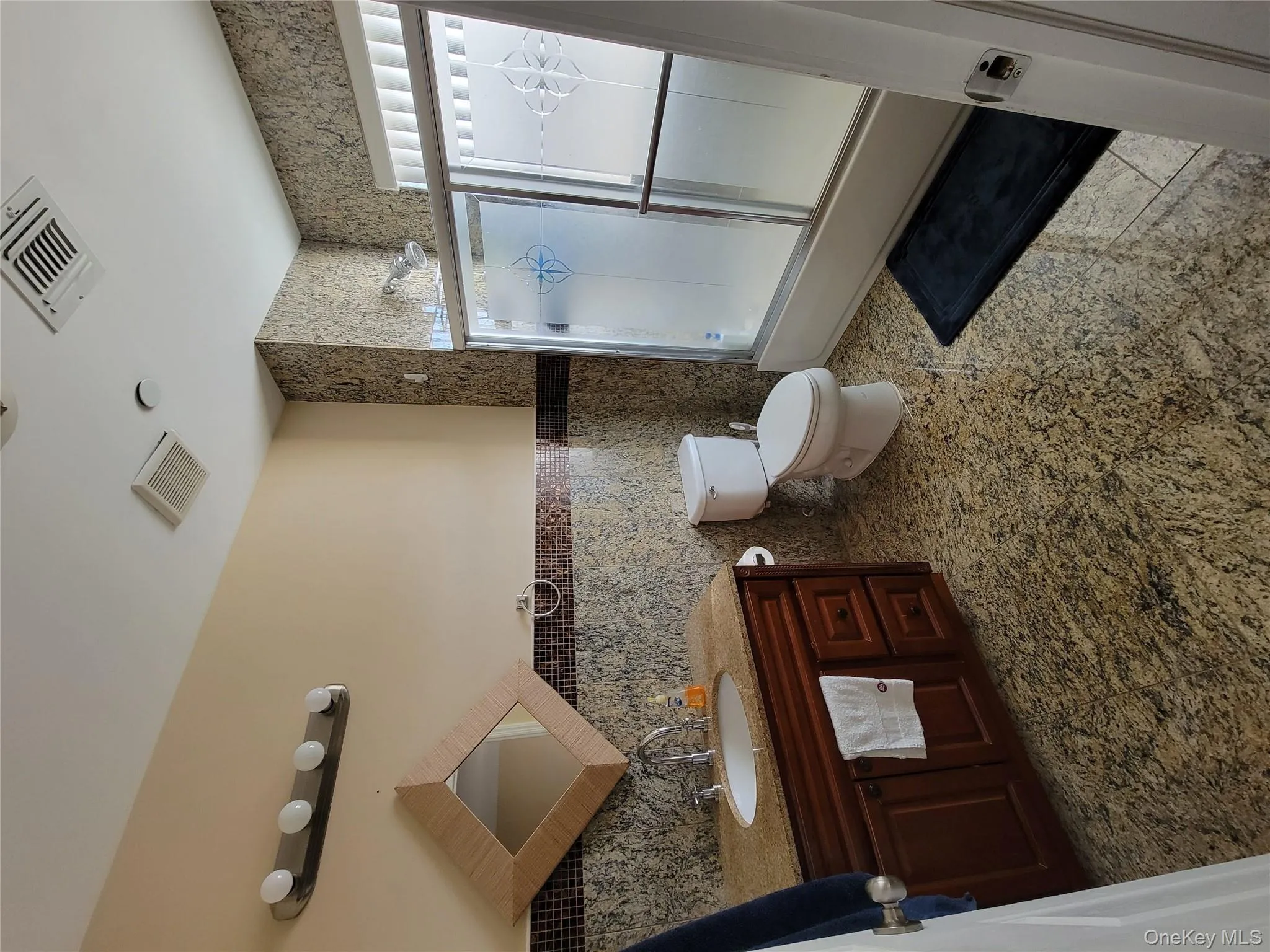 Bathroom with tile walls, vanity, bath / shower combo with glass door, and wainscoting Bathroom with tile walls, vanity, bath / shower combo with glass door, and wainscoting