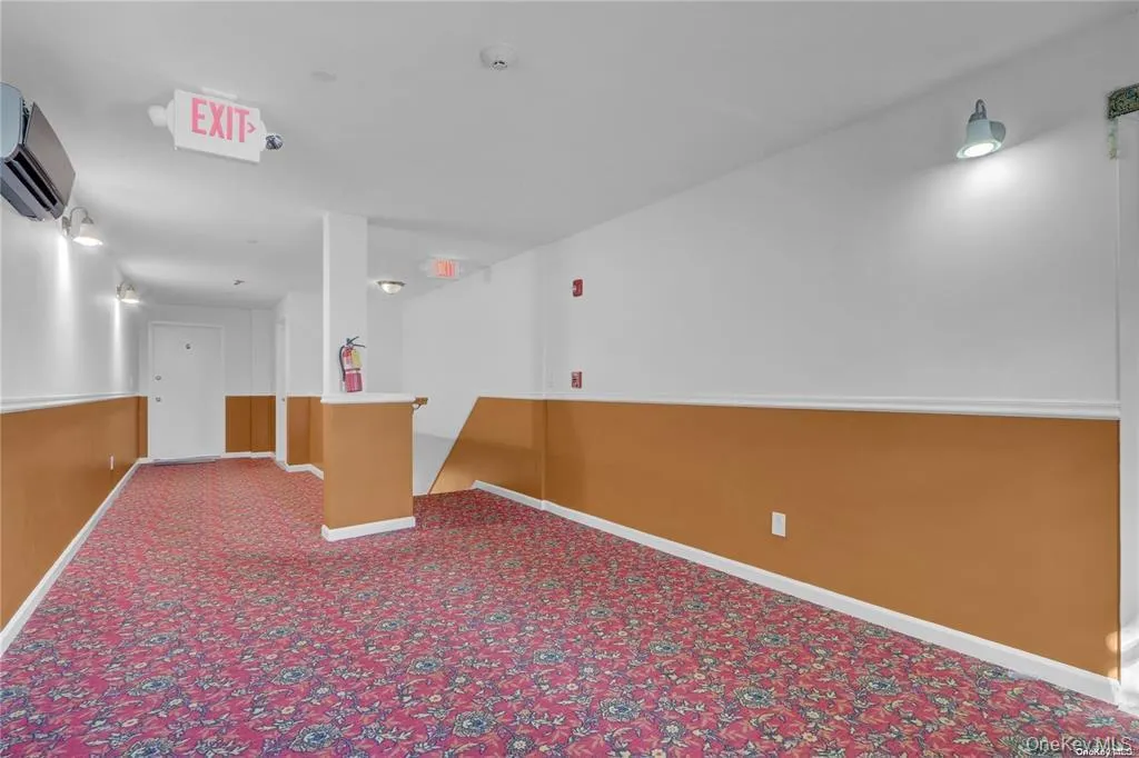 Carpeted spare room with a wall mounted air conditioner and baseboards Carpeted spare room with a wall mounted air conditioner and baseboards