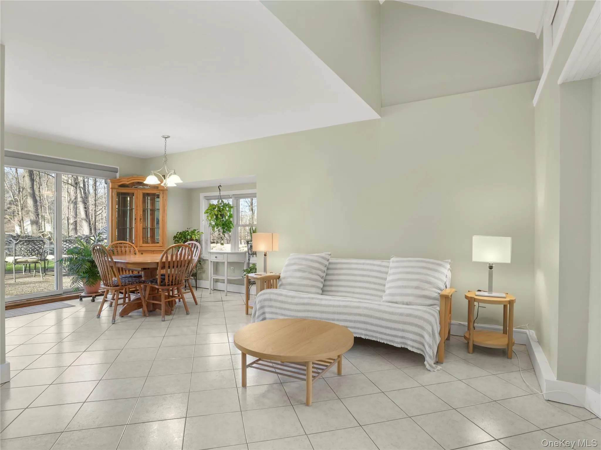 Living room featuring light tile patterned floors, a chandelier, and vaulted ceiling Living room featuring light tile patterned floors, a chandelier, and vaulted ceiling
