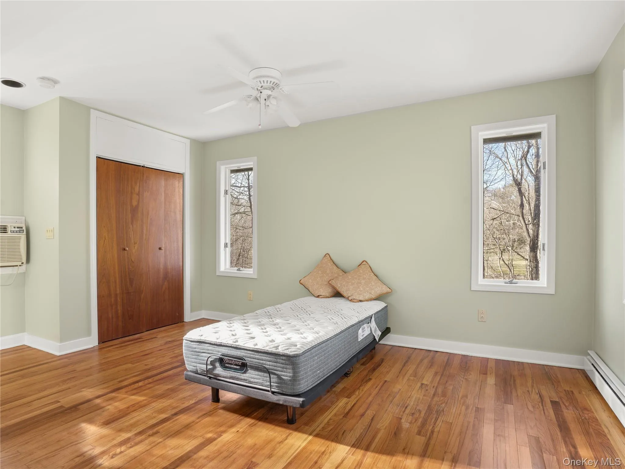 Bedroom featuring wood floors, baseboard heating, a ceiling fan, a closet. Bedroom featuring wood floors, baseboard heating, a ceiling fan, a closet.