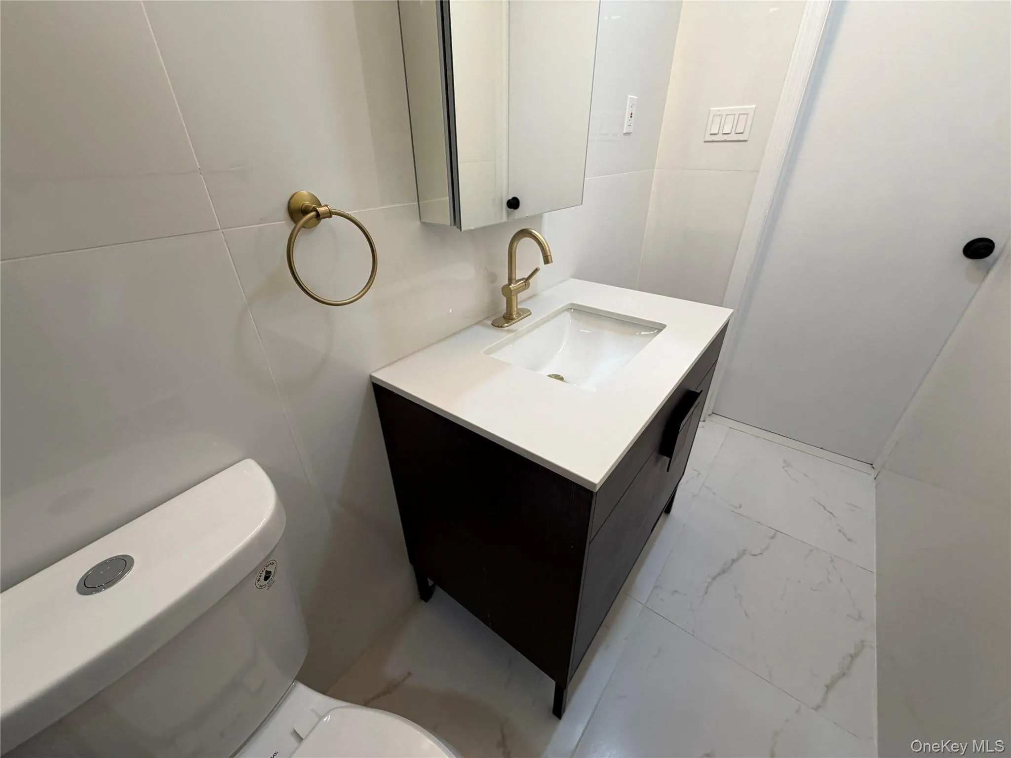 Bathroom with light marble finish floors, vanity, and tile walls Bathroom with light marble finish floors, vanity, and tile walls