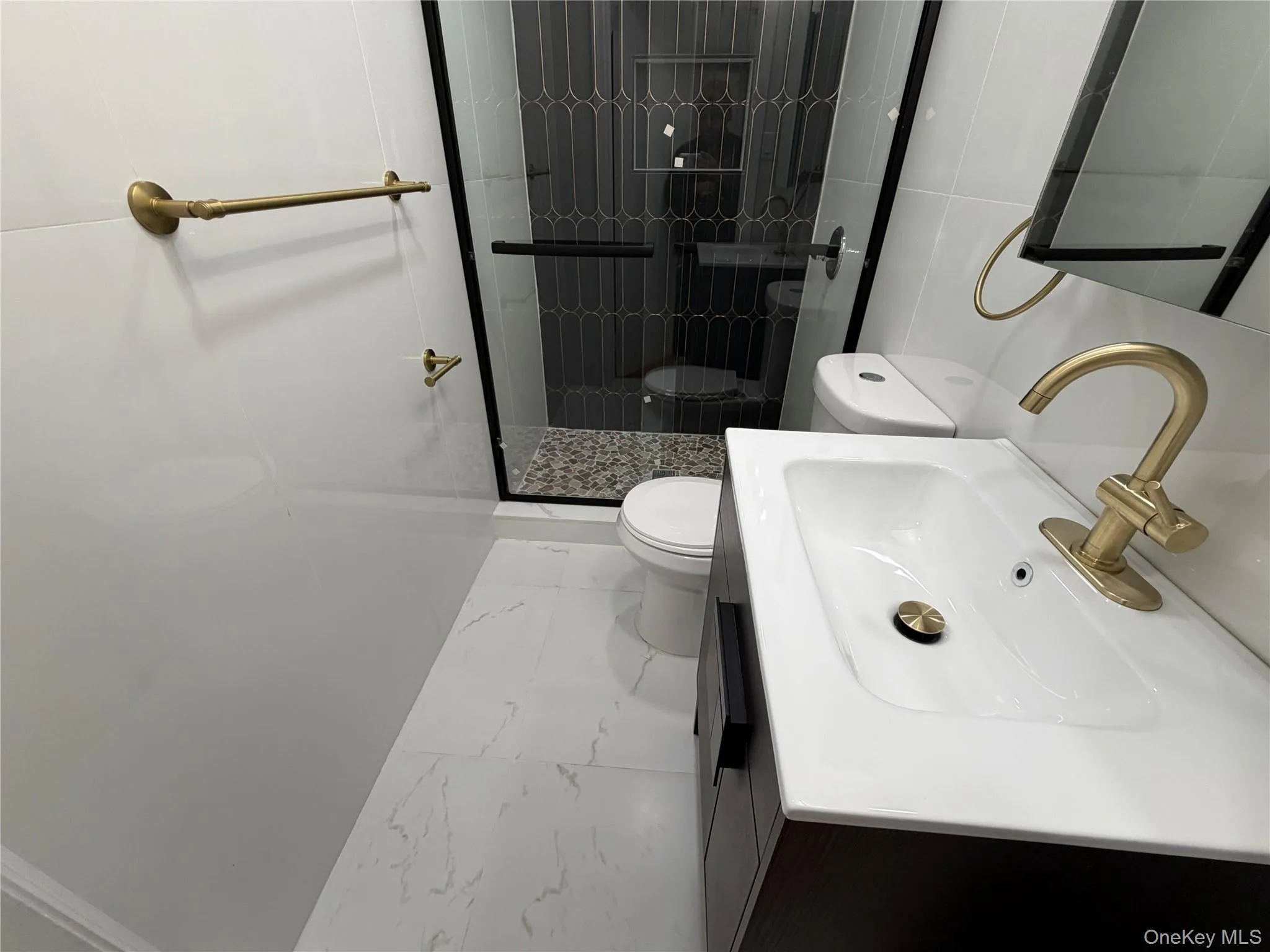 Bathroom featuring vanity, marble look tiles, a stall shower, and tile walls Bathroom featuring vanity, marble look tiles, a stall shower, and tile walls
