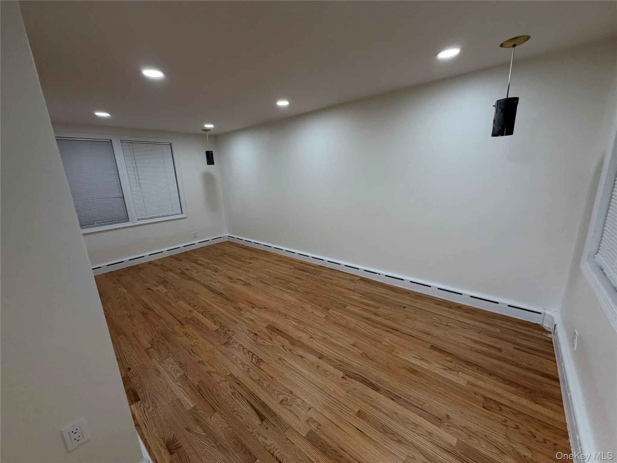 Empty room featuring light wood finished floors, baseboard heating, and recessed lighting Empty room featuring light wood finished floors, baseboard heating, and recessed lighting