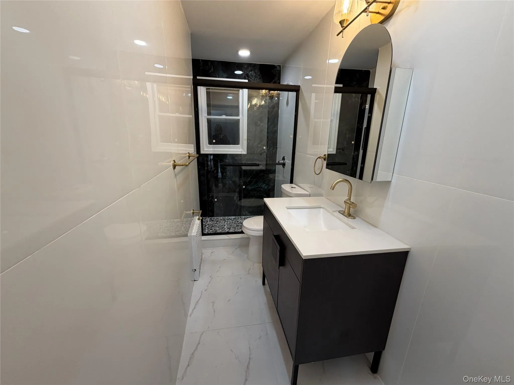 Bathroom featuring light marble finish floors, a marble finish shower, vanity, and recessed lighting Bathroom featuring light marble finish floors, a marble finish shower, vanity, and recessed lighting