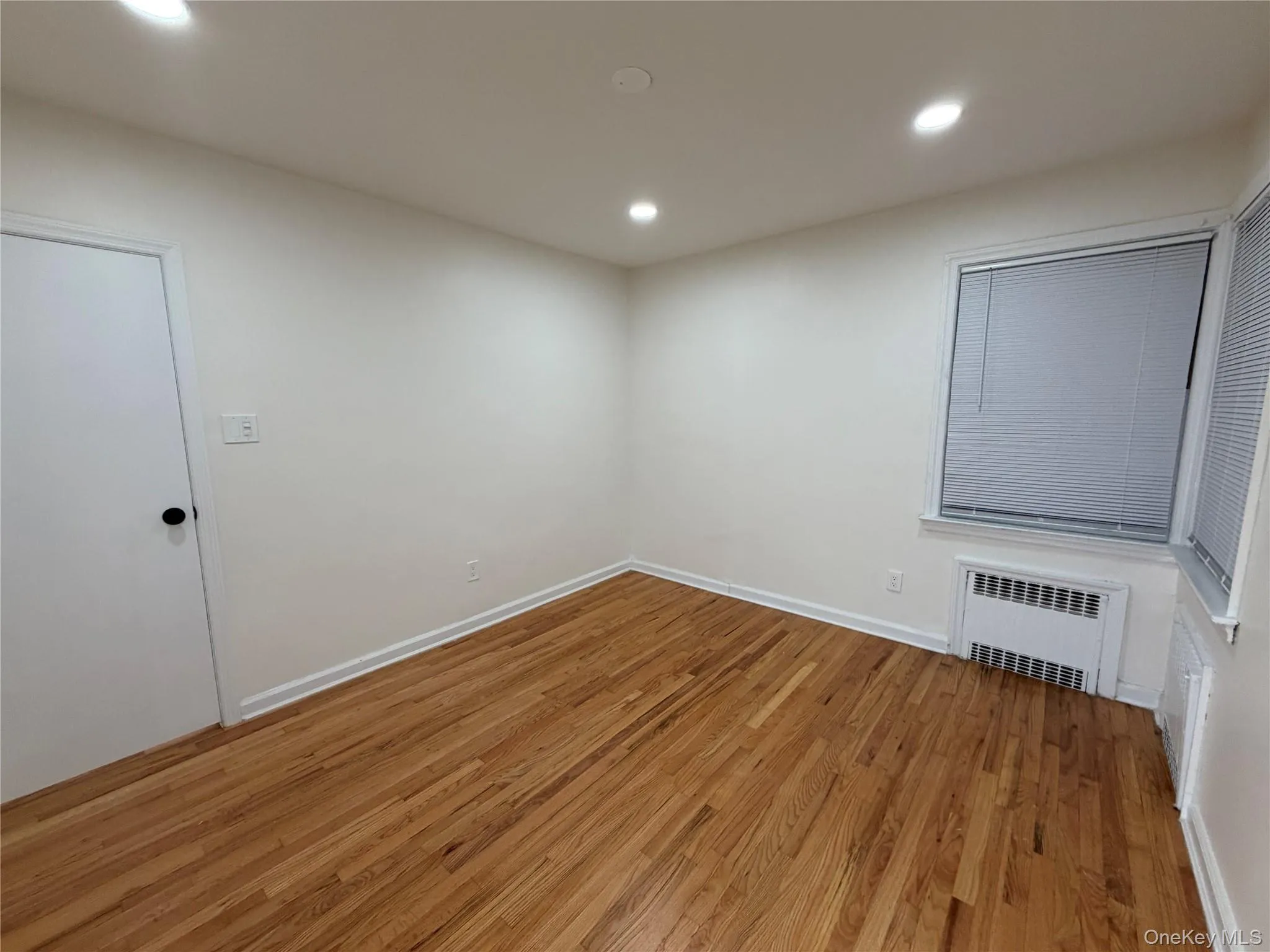 Spare room with light wood-style floors, radiator, and recessed lighting Spare room with light wood-style floors, radiator, and recessed lighting