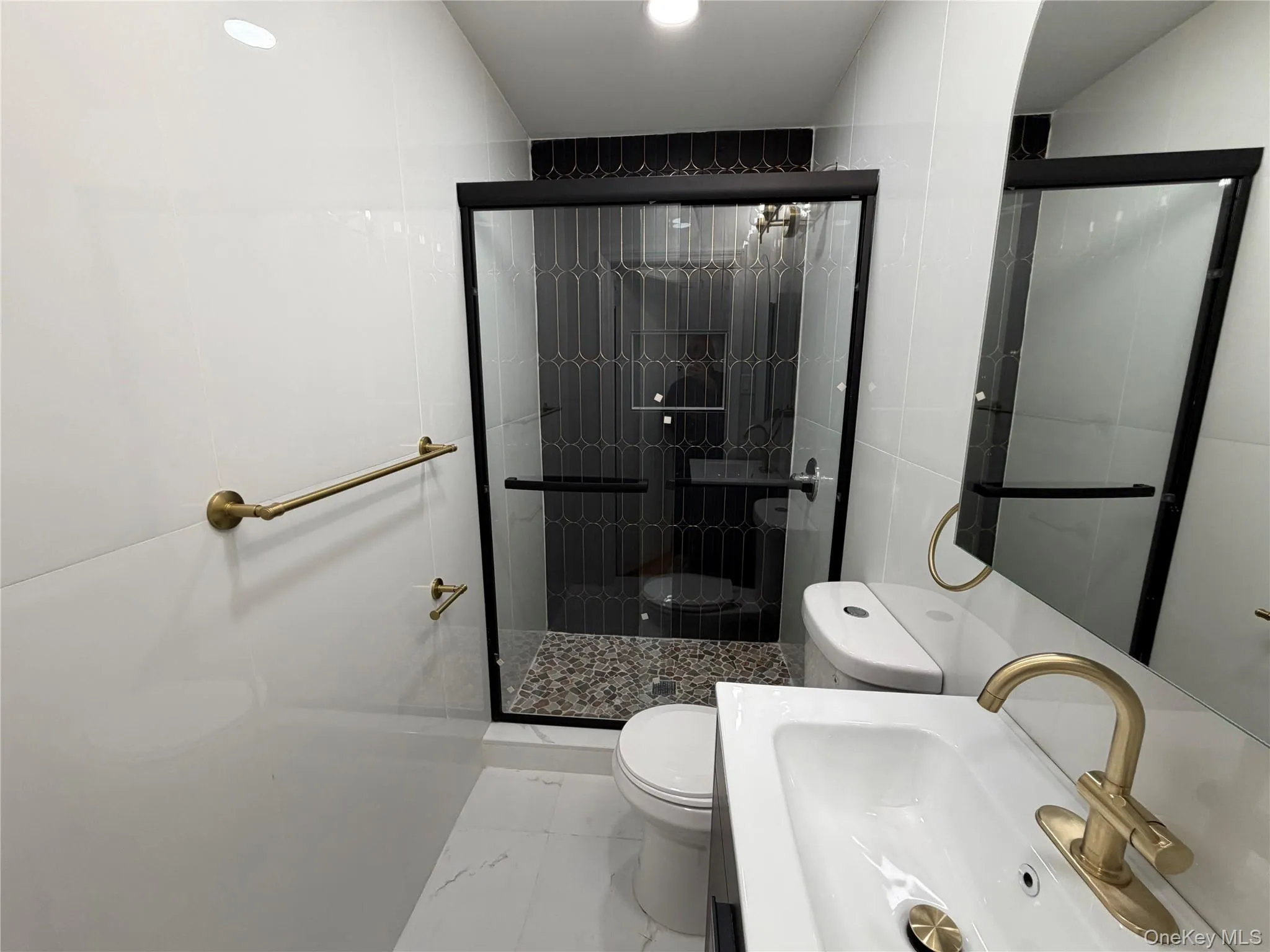 Bathroom featuring vanity, a shower stall, tile walls, and marble look tile flooring Bathroom featuring vanity, a shower stall, tile walls, and marble look tile flooring