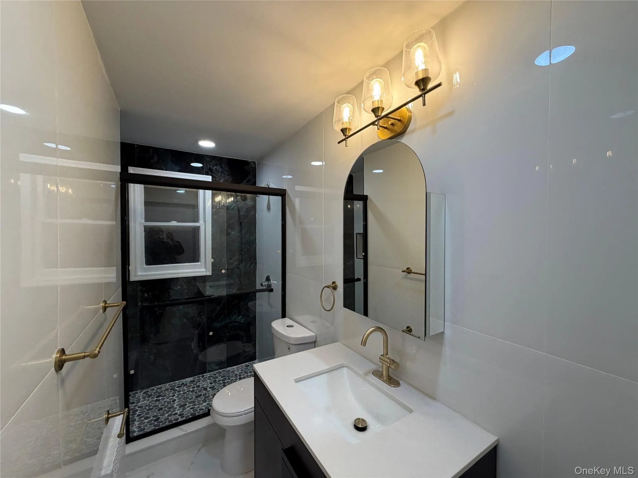 Full bath with vanity, a marble finish shower, and tile walls Full bath with vanity, a marble finish shower, and tile walls