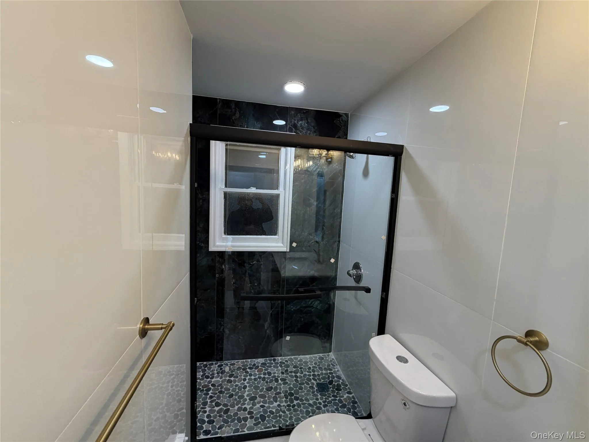 Bathroom with tile walls, a stall shower, and recessed lighting Bathroom with tile walls, a stall shower, and recessed lighting
