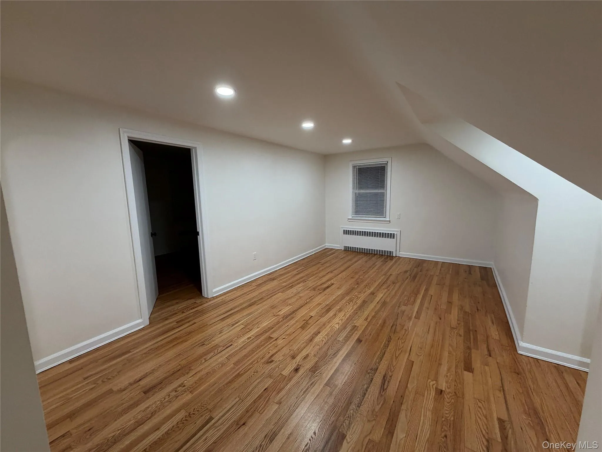 Additional living space with light wood finished floors, recessed lighting, and radiator heating unit Additional living space with light wood finished floors, recessed lighting, and radiator heating unit