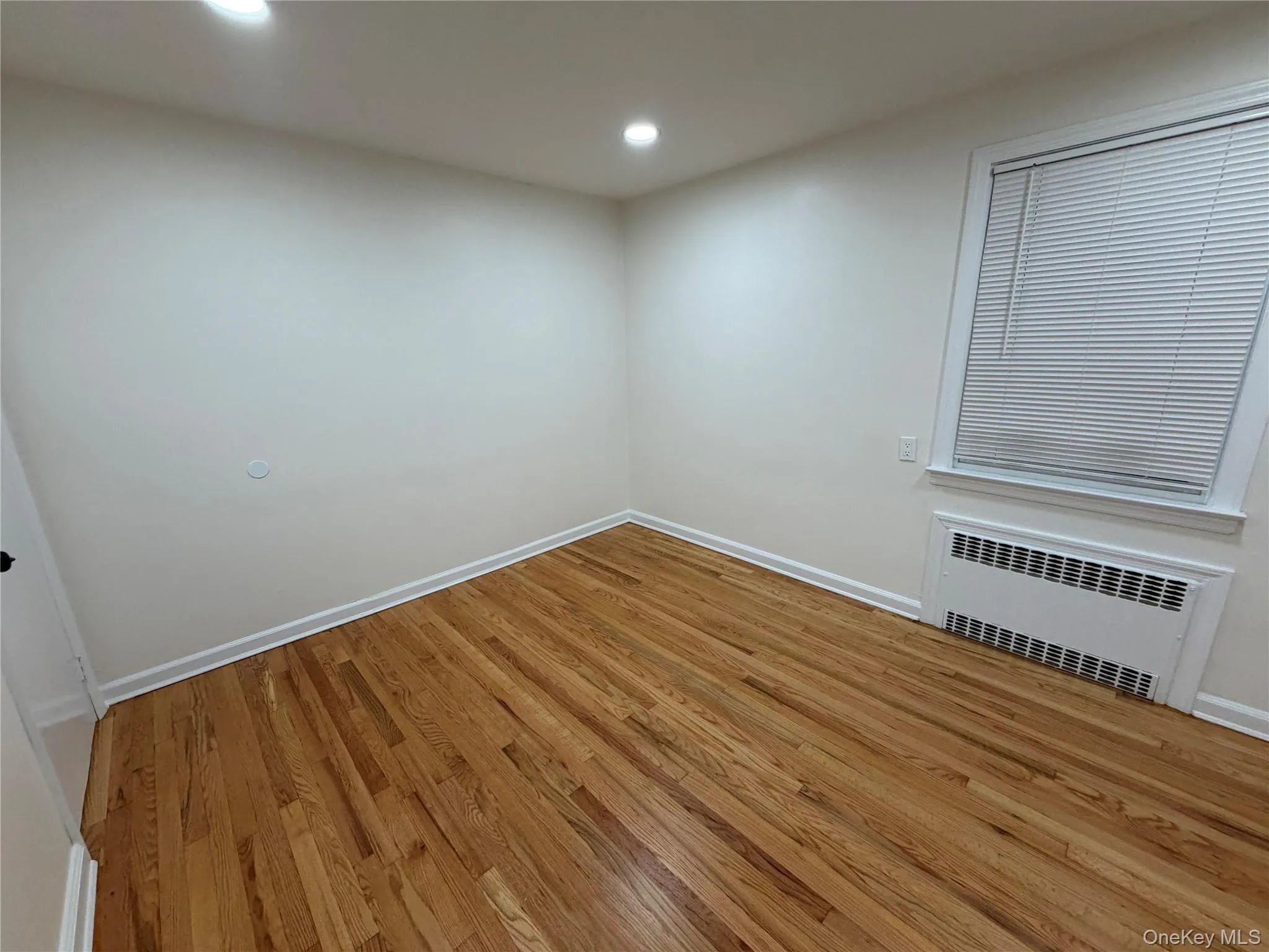 Unfurnished room with light wood-style flooring, radiator, and recessed lighting Unfurnished room with light wood-style flooring, radiator, and recessed lighting