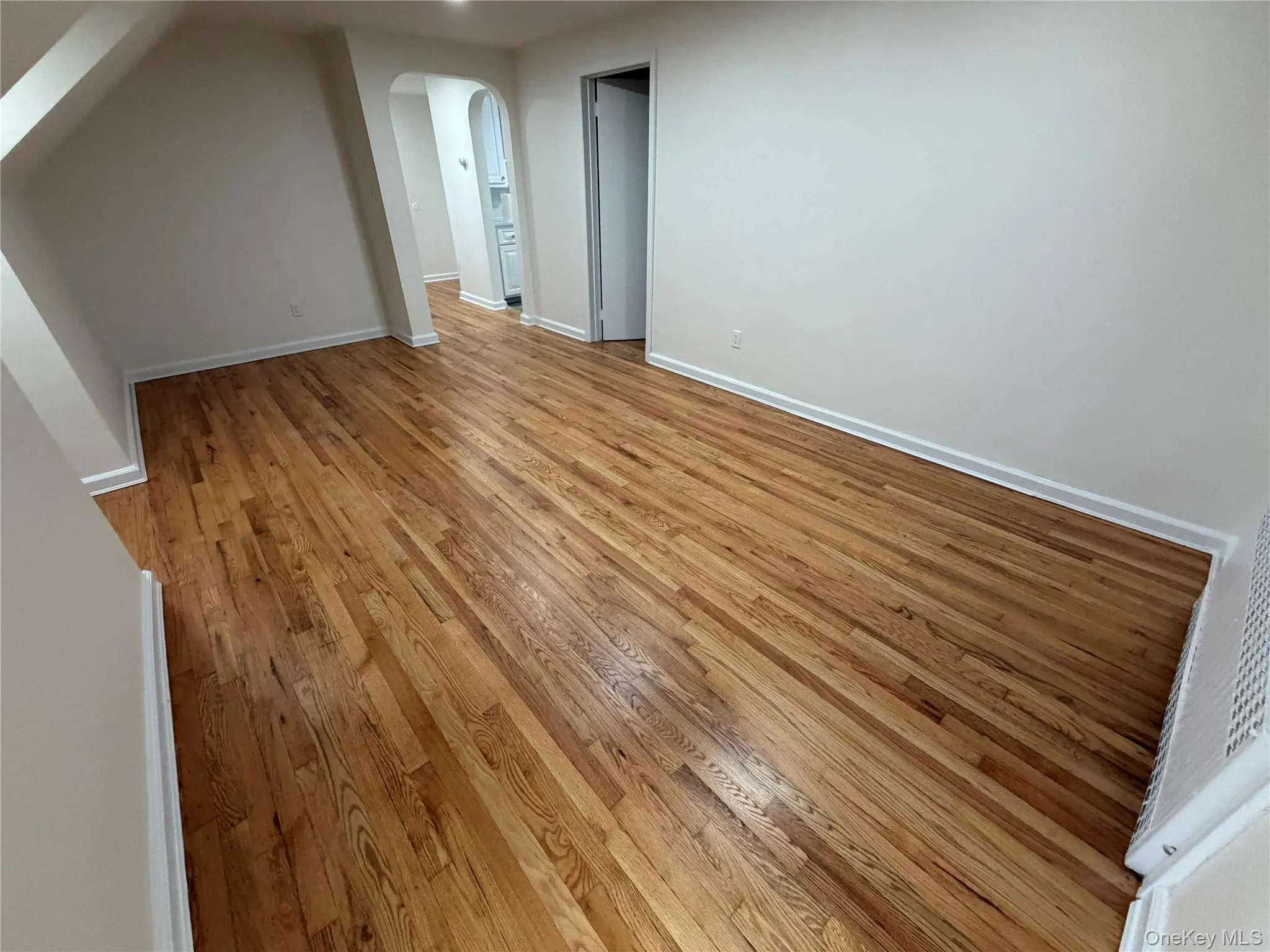 Bonus room featuring light wood-style floors and arched walkways Bonus room featuring light wood-style floors and arched walkways