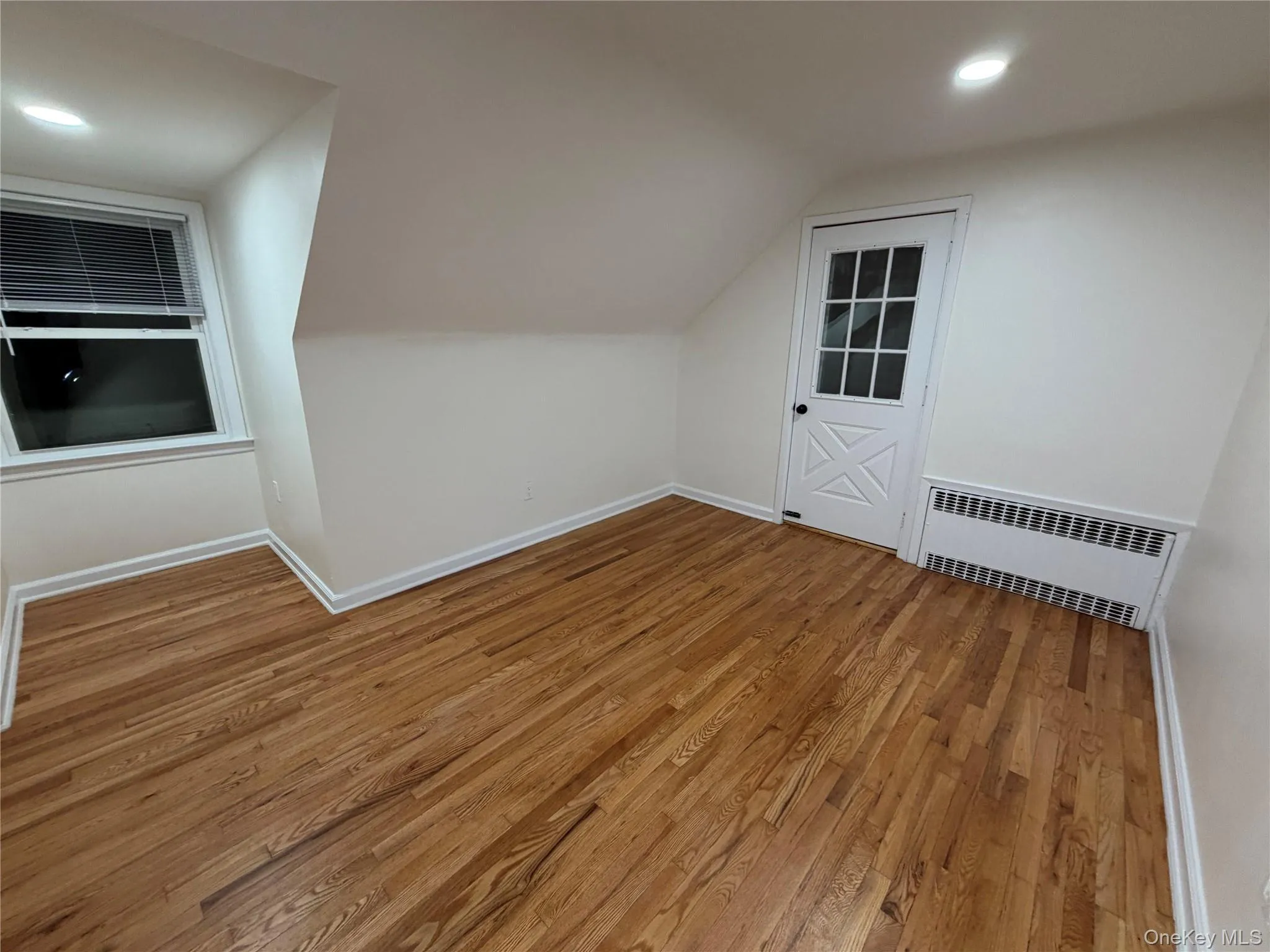 Bonus room with recessed lighting, light wood-style floors, radiator heating unit, and vaulted ceiling Bonus room with recessed lighting, light wood-style floors, radiator heating unit, and vaulted ceiling