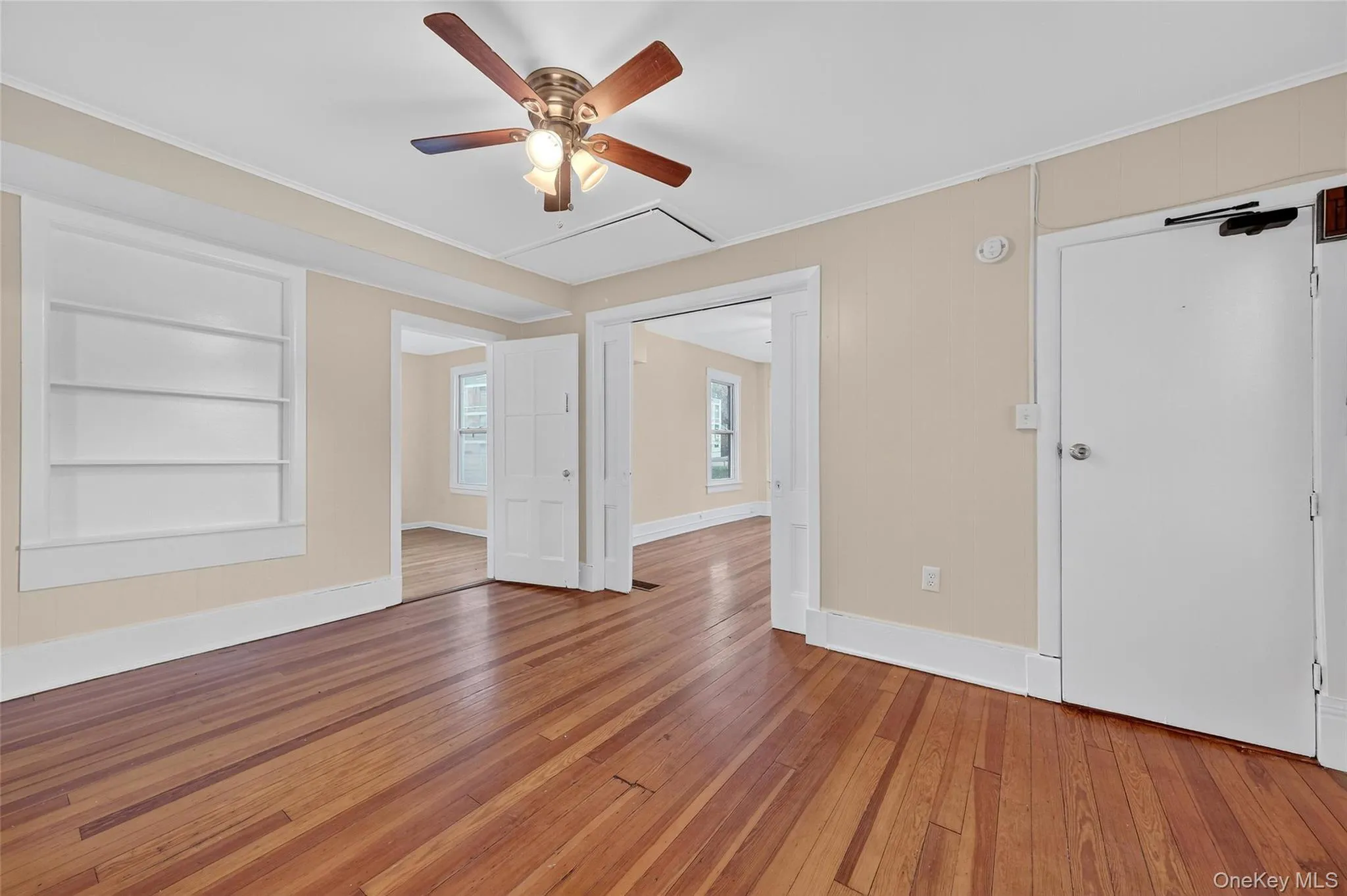 Spare room featuring built in features, crown molding, hardwood / wood-style floors, and ceiling fan Spare room featuring built in features, crown molding, hardwood / wood-style floors, and ceiling fan