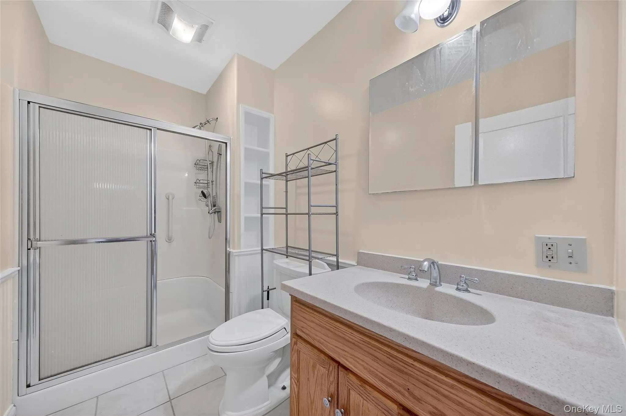 Bathroom with light tile patterned floors, vanity, and a shower stall Bathroom with light tile patterned floors, vanity, and a shower stall