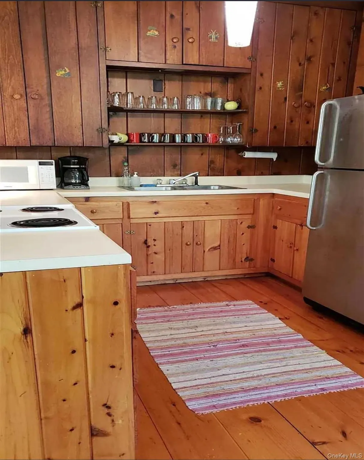 Kitchen featuring open shelves, freestanding refrigerator, light countertops, and light wood floors Kitchen featuring open shelves, freestanding refrigerator, light countertops, and light wood floors