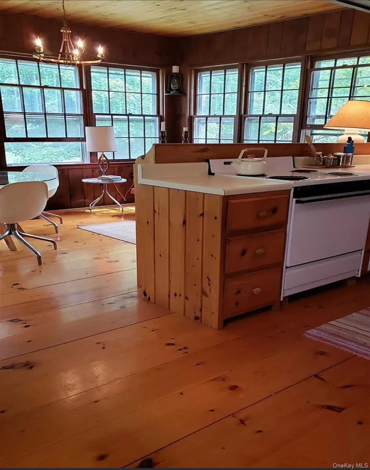 Kitchen featuring wood ceiling, wood walls, light wood-style floors, electric range, and healthy amount of natural light. Opens to Dining Area. Kitchen featuring wood ceiling, wood walls, light wood-style floors, electric range, and healthy amount of natural light. Opens to Dining Area.