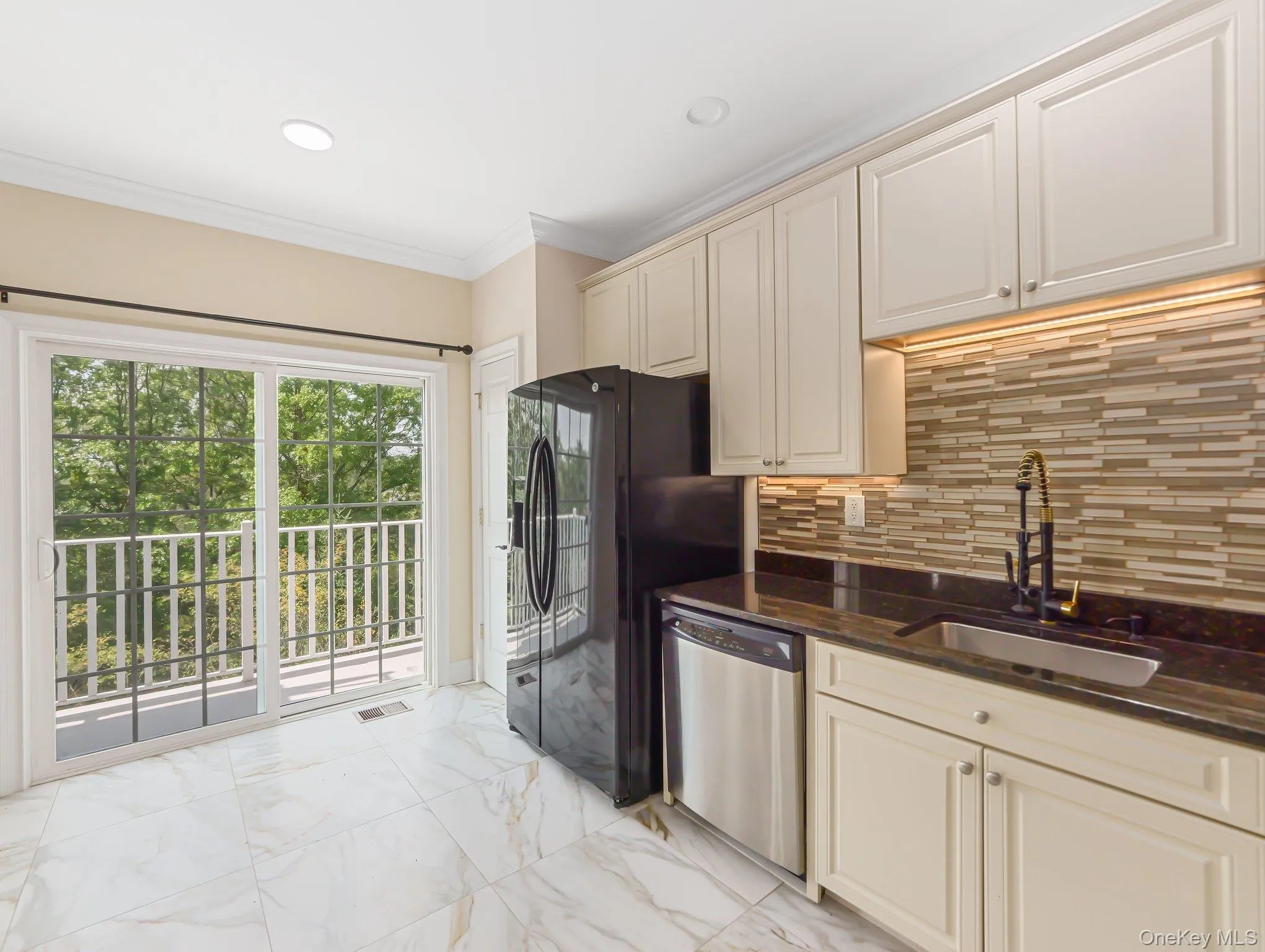 Kitchen with decorative backsplash, dark stone counters, light marble finish floors, dishwasher, and crown molding Kitchen with decorative backsplash, dark stone counters, light marble finish floors, dishwasher, and crown molding