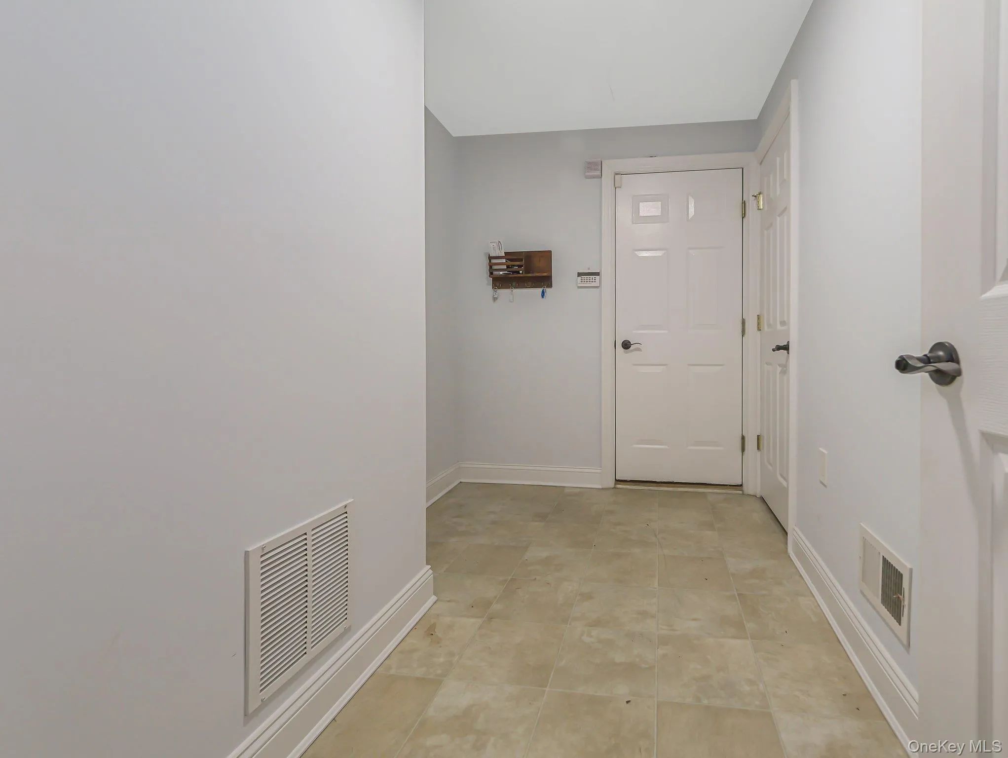 Hallway featuring baseboards and light tile patterned floors Hallway featuring baseboards and light tile patterned floors