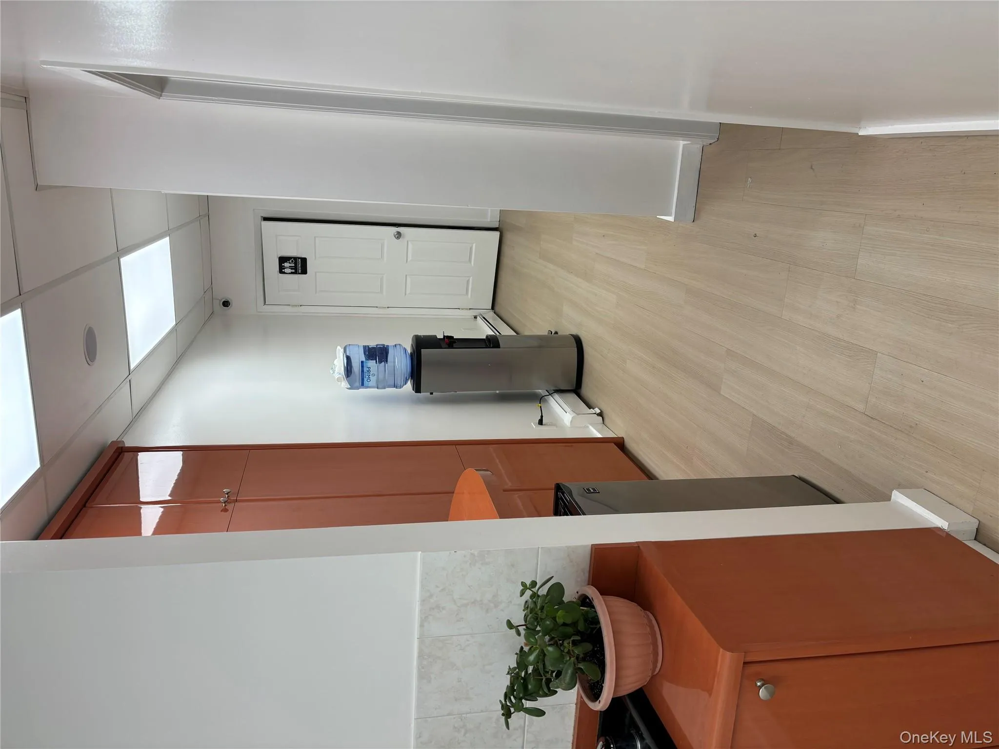 Hallway featuring a drop ceiling, light wood-style floors, and a baseboard radiator Hallway featuring a drop ceiling, light wood-style floors, and a baseboard radiator
