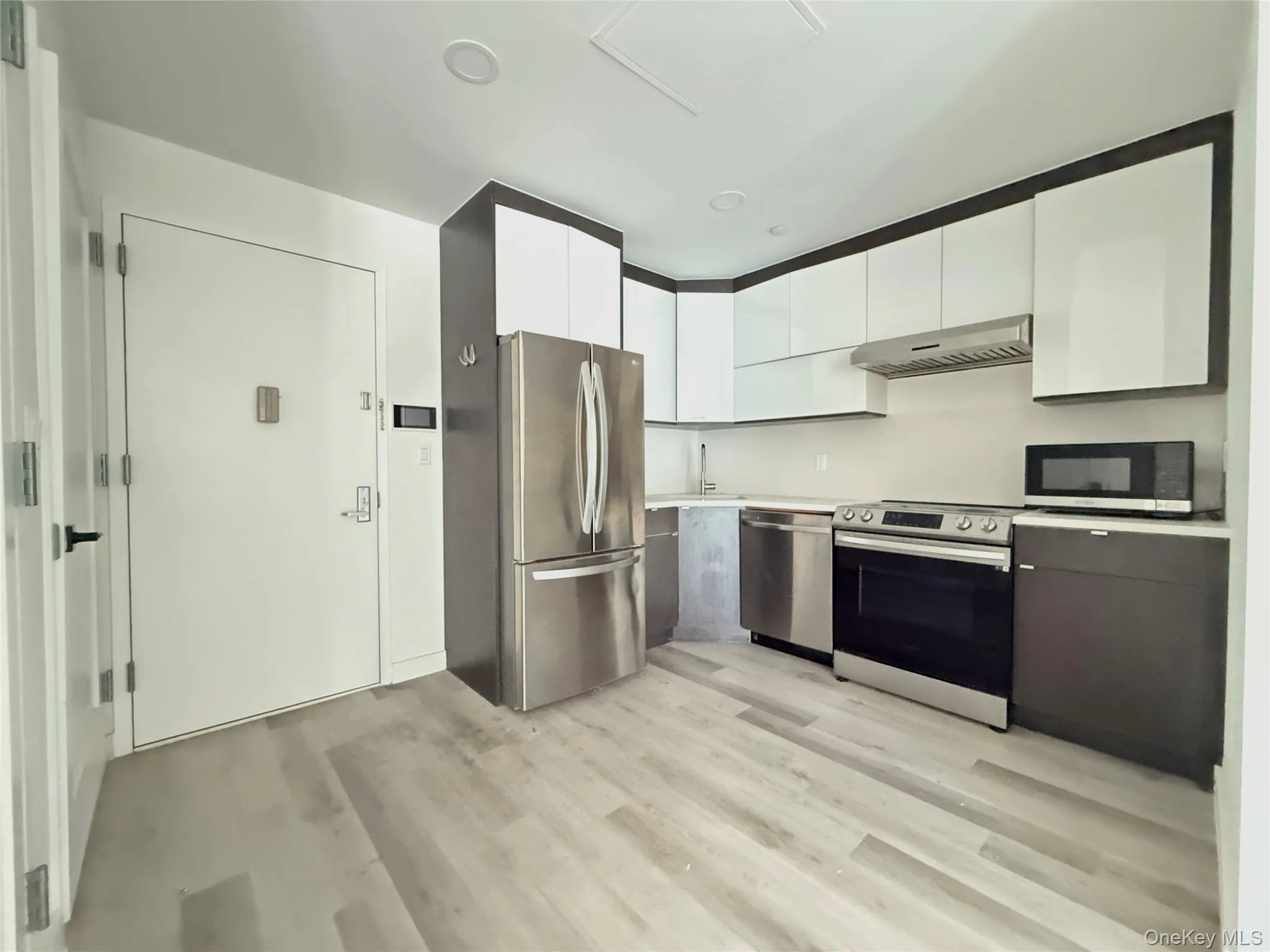 Kitchen with white cabinetry, stainless steel appliances, light countertops, modern cabinets, and light wood-type flooring Kitchen with white cabinetry, stainless steel appliances, light countertops, modern cabinets, and light wood-type flooring