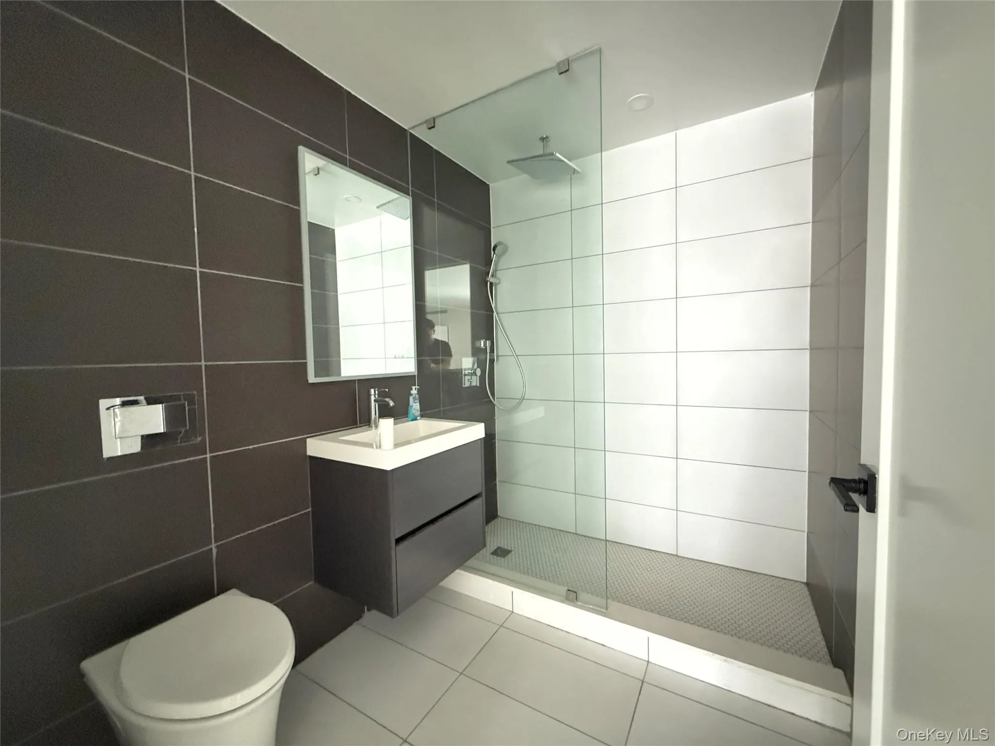 Full bathroom featuring vanity, walk in shower, light tile patterned floors, and tile walls Full bathroom featuring vanity, walk in shower, light tile patterned floors, and tile walls