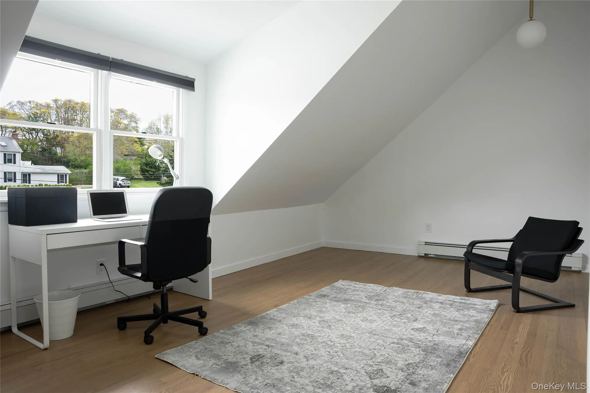 Home office featuring light wood finished floors, a baseboard heating unit, and lofted ceiling Home office featuring light wood finished floors, a baseboard heating unit, and lofted ceiling