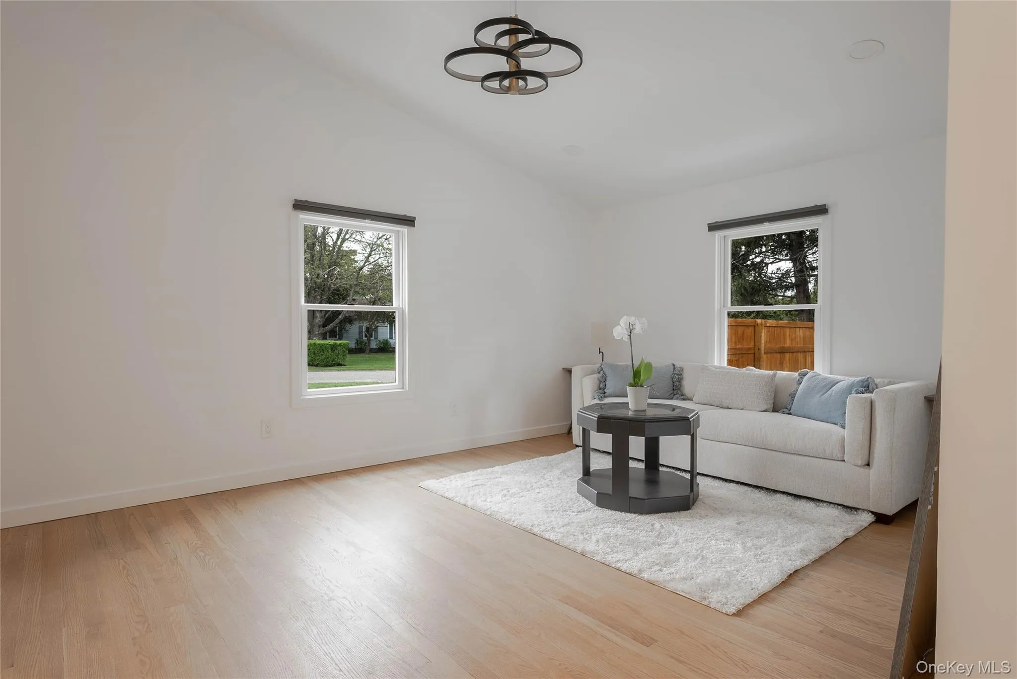 Living room featuring lofted ceiling, plenty of natural light, and light wood-style flooring Living room featuring lofted ceiling, plenty of natural light, and light wood-style flooring