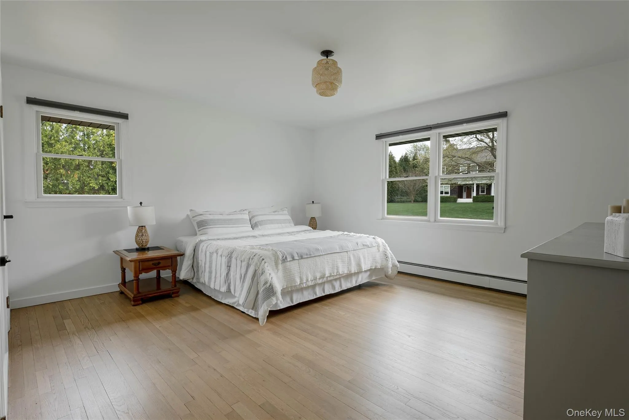 Bedroom featuring multiple windows, a baseboard radiator, and light wood-style floors Bedroom featuring multiple windows, a baseboard radiator, and light wood-style floors