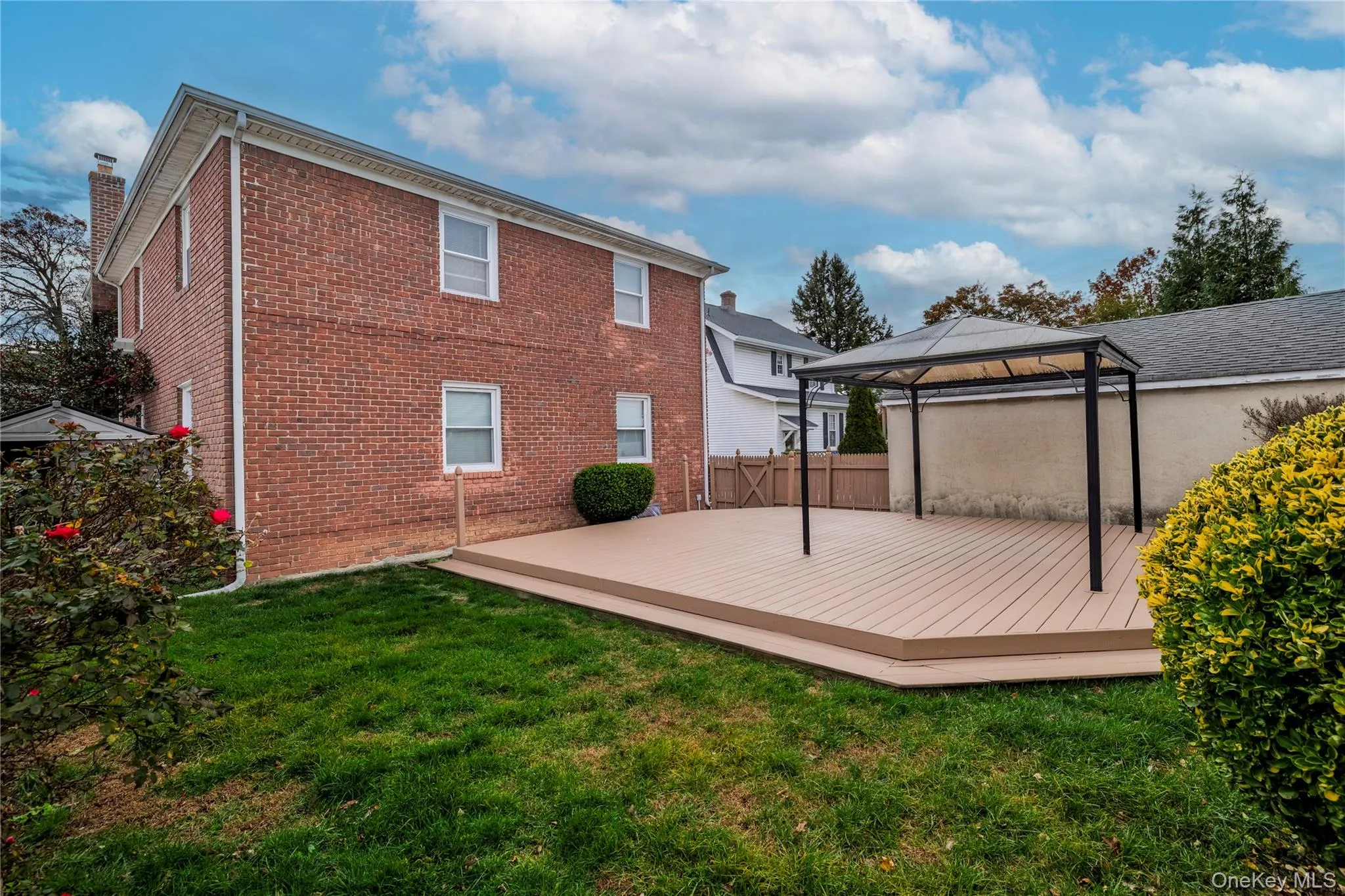 Back of house featuring a gazebo, a deck, brick siding, and a lawn Back of house featuring a gazebo, a deck, brick siding, and a lawn