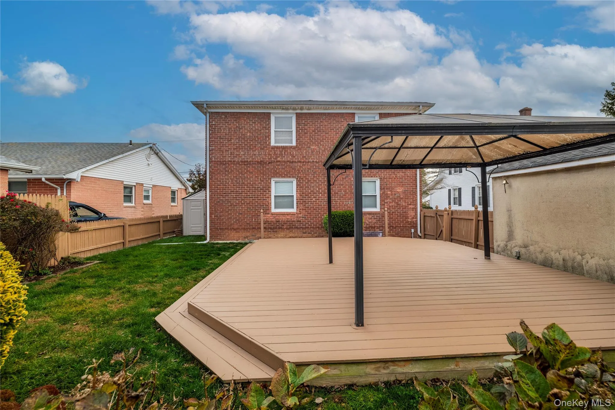 Rear view of house with a wooden deck, brick siding, a fenced backyard, and a gazebo Rear view of house with a wooden deck, brick siding, a fenced backyard, and a gazebo