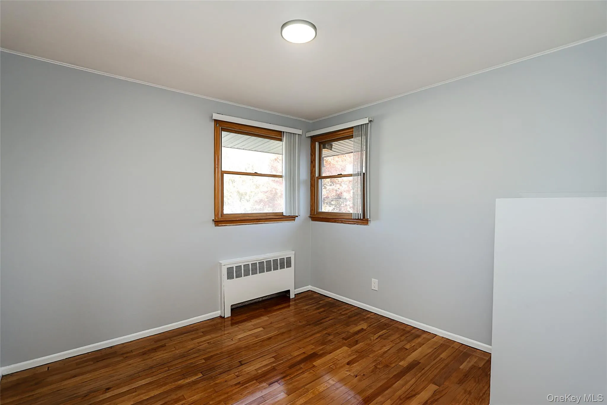 Unfurnished room with radiator heating unit, dark wood-type flooring, and crown molding Unfurnished room with radiator heating unit, dark wood-type flooring, and crown molding