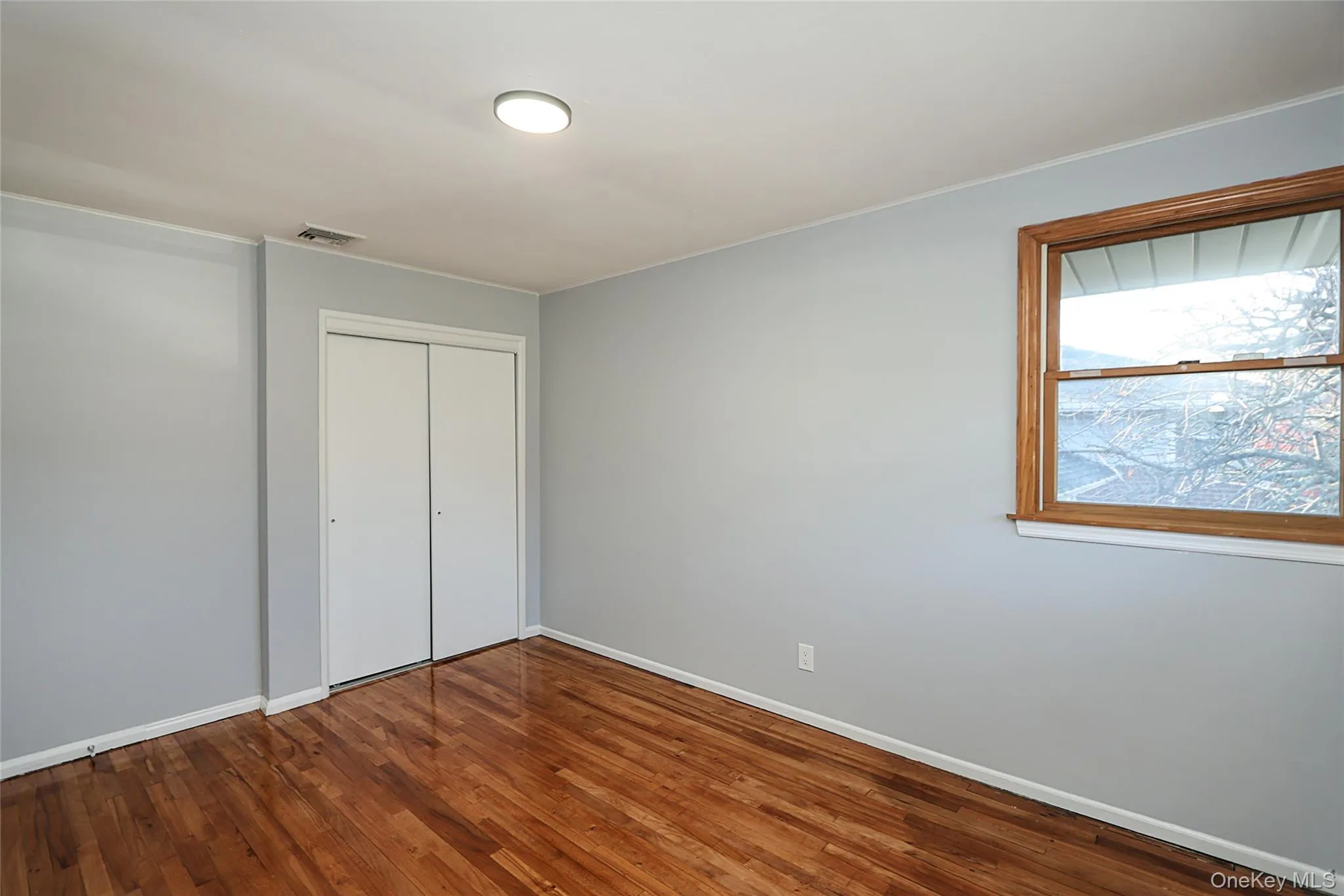 Unfurnished bedroom with a closet and dark wood finished floors Unfurnished bedroom with a closet and dark wood finished floors