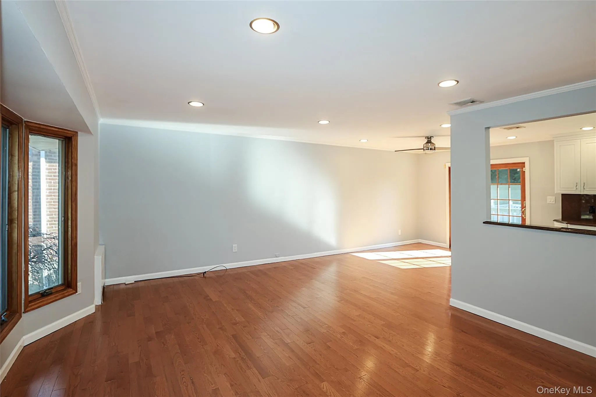 Unfurnished living room with dark wood-style flooring, recessed lighting, ceiling fan, and ornamental molding Unfurnished living room with dark wood-style flooring, recessed lighting, ceiling fan, and ornamental molding
