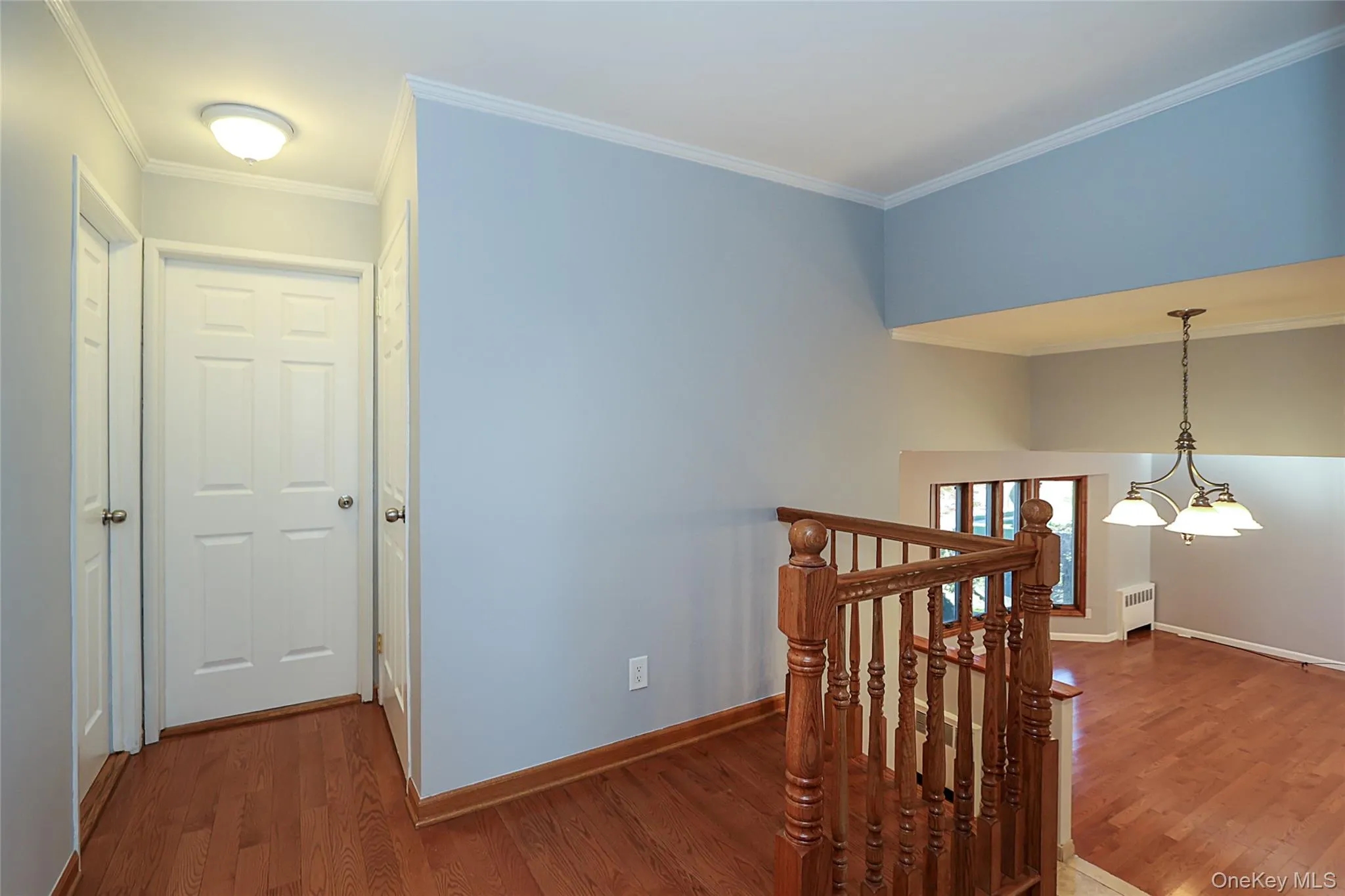 Corridor featuring crown molding, dark wood finished floors, an upstairs landing, a chandelier, and radiator Corridor featuring crown molding, dark wood finished floors, an upstairs landing, a chandelier, and radiator