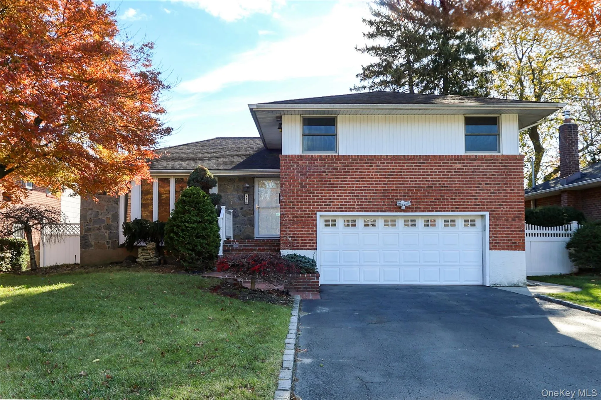 Tri-level home with driveway, an attached garage, and brick siding Tri-level home with driveway, an attached garage, and brick siding