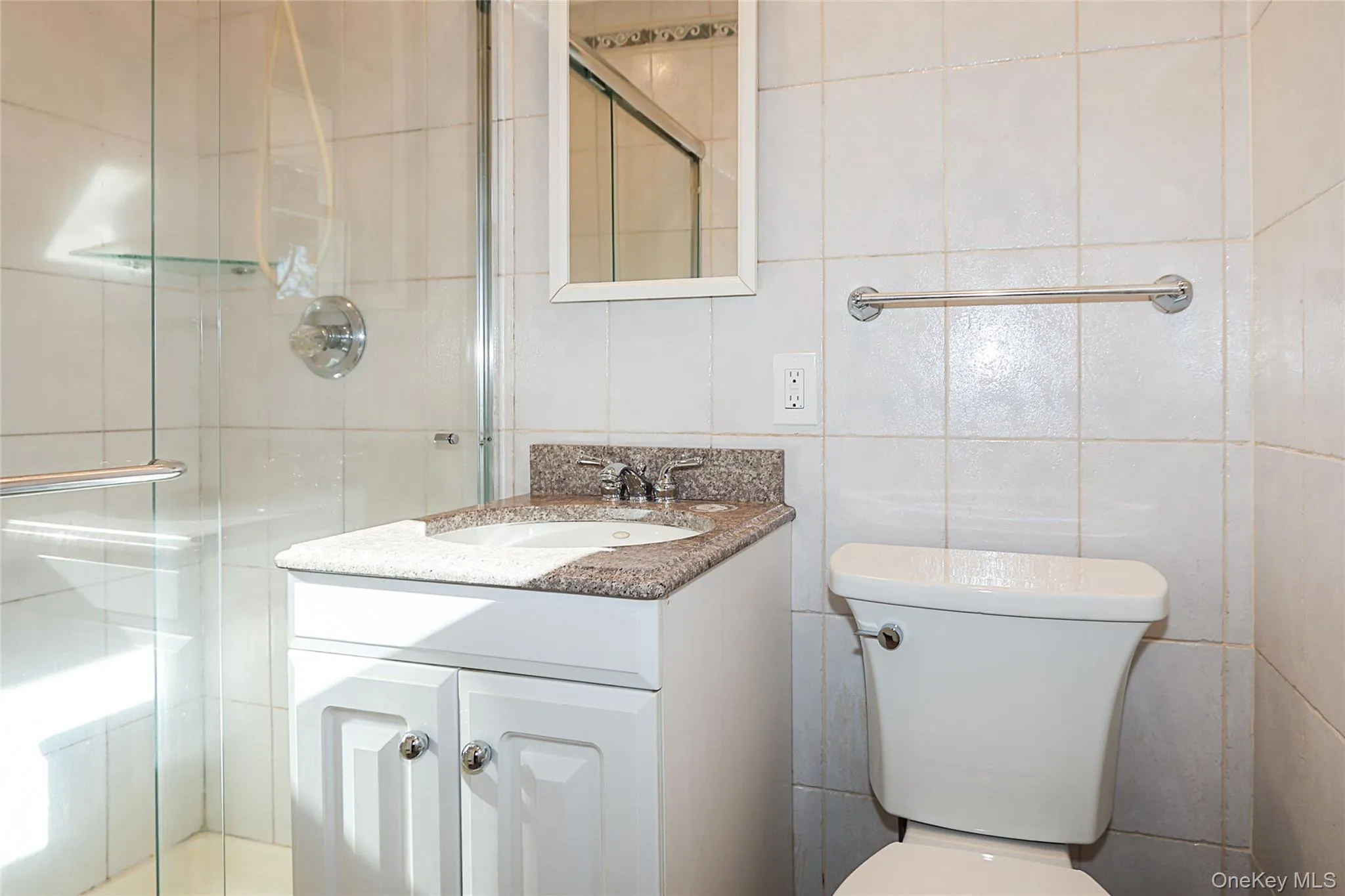 Bathroom featuring tile walls, a stall shower, and vanity Bathroom featuring tile walls, a stall shower, and vanity