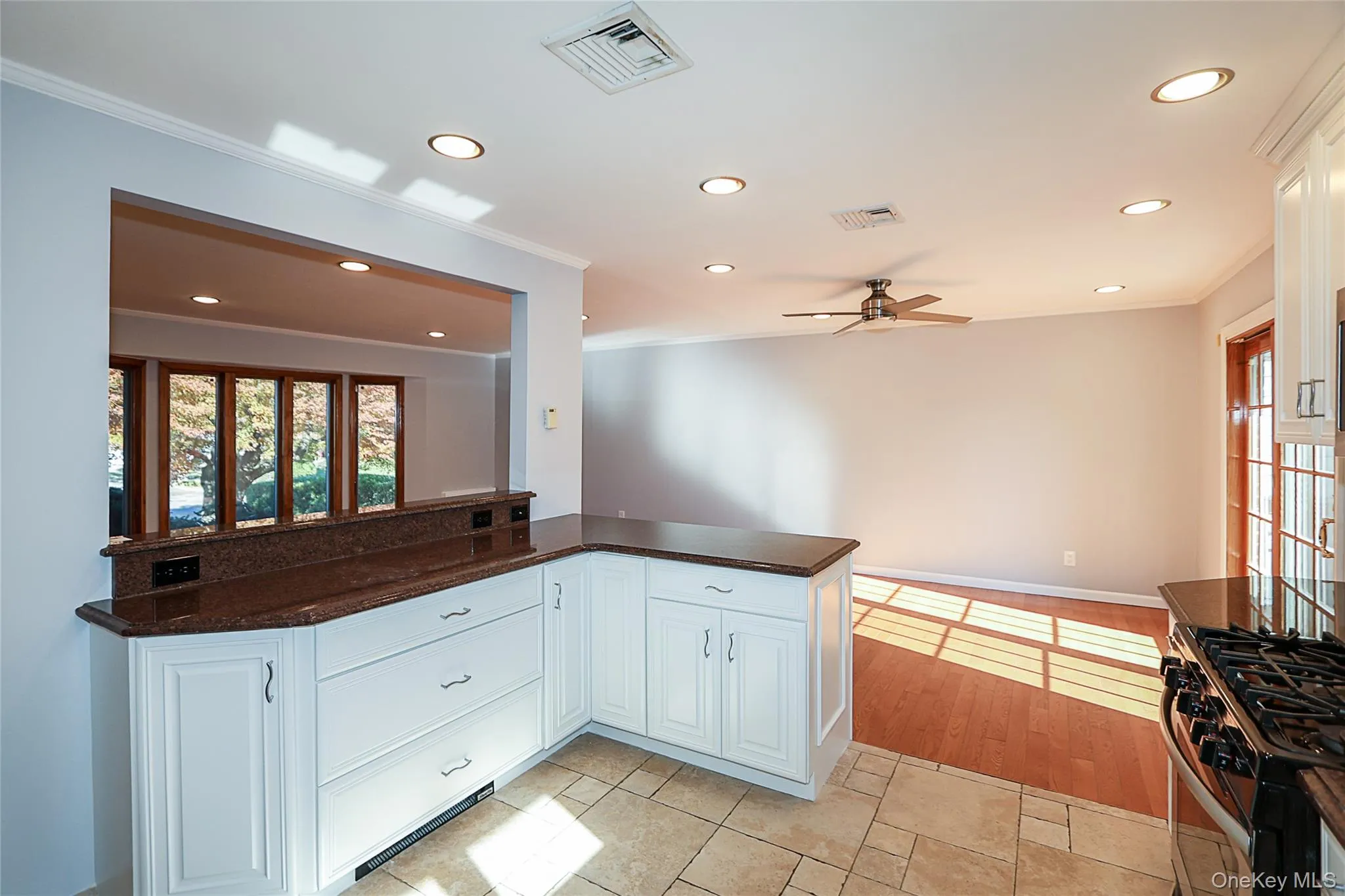Kitchen featuring white cabinetry, recessed lighting, a ceiling fan, ornamental molding, and dark stone counters Kitchen featuring white cabinetry, recessed lighting, a ceiling fan, ornamental molding, and dark stone counters