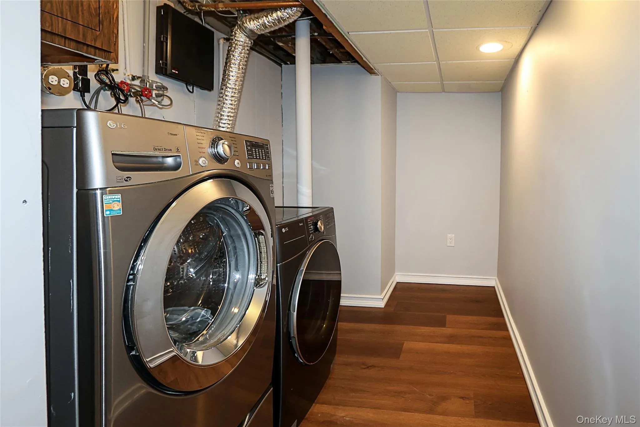 Laundry area with dark wood-style floors, washing machine and clothes dryer, a drop ceiling, and recessed lighting Laundry area with dark wood-style floors, washing machine and clothes dryer, a drop ceiling, and recessed lighting