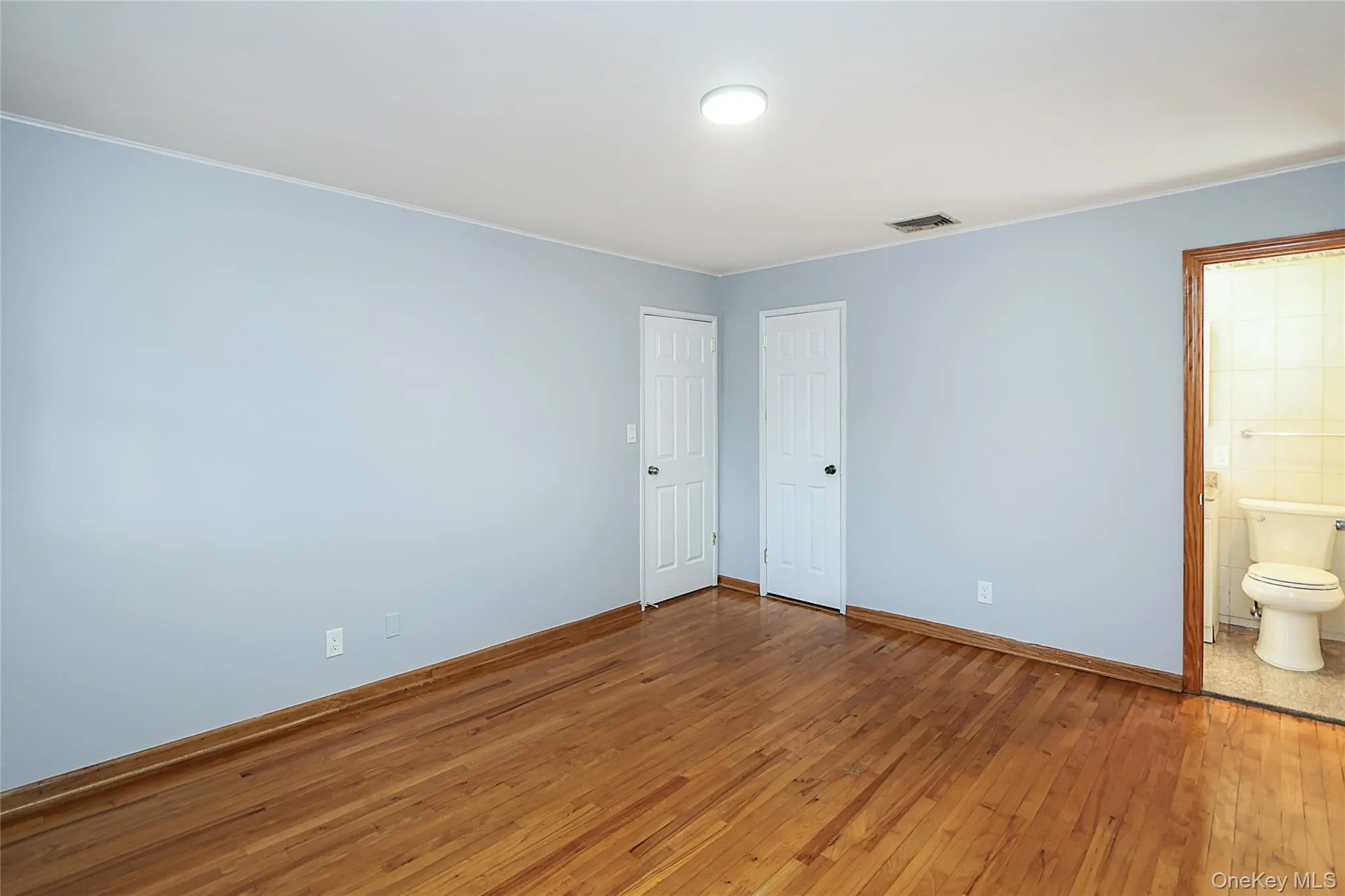 Unfurnished bedroom featuring hardwood / wood-style floors, ensuite bathroom, and crown molding Unfurnished bedroom featuring hardwood / wood-style floors, ensuite bathroom, and crown molding