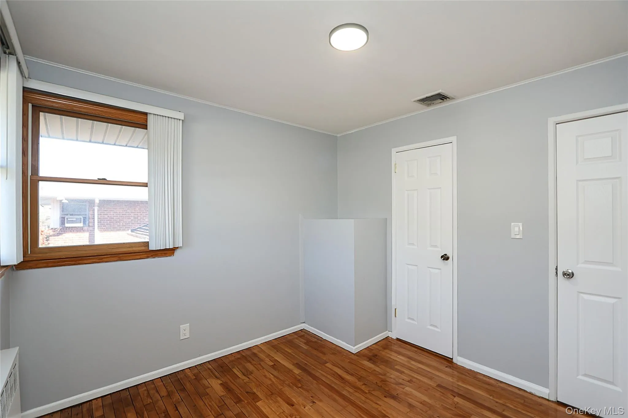 Unfurnished bedroom featuring dark wood-style floors and ornamental molding Unfurnished bedroom featuring dark wood-style floors and ornamental molding