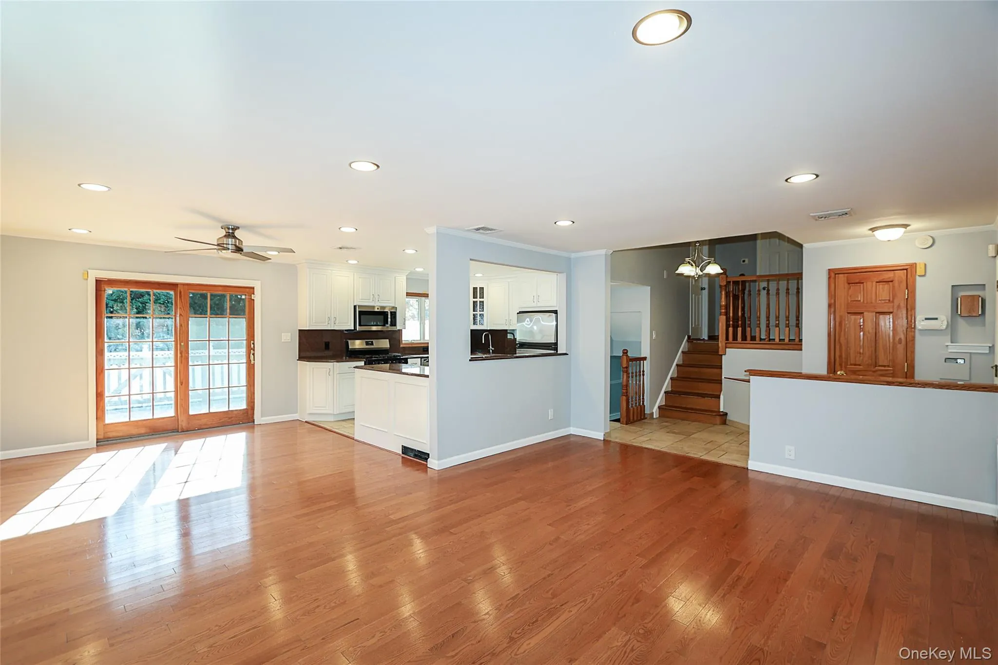 Unfurnished living room featuring recessed lighting, light wood-style flooring, ceiling fan, stairway, and ornamental molding Unfurnished living room featuring recessed lighting, light wood-style flooring, ceiling fan, stairway, and ornamental molding