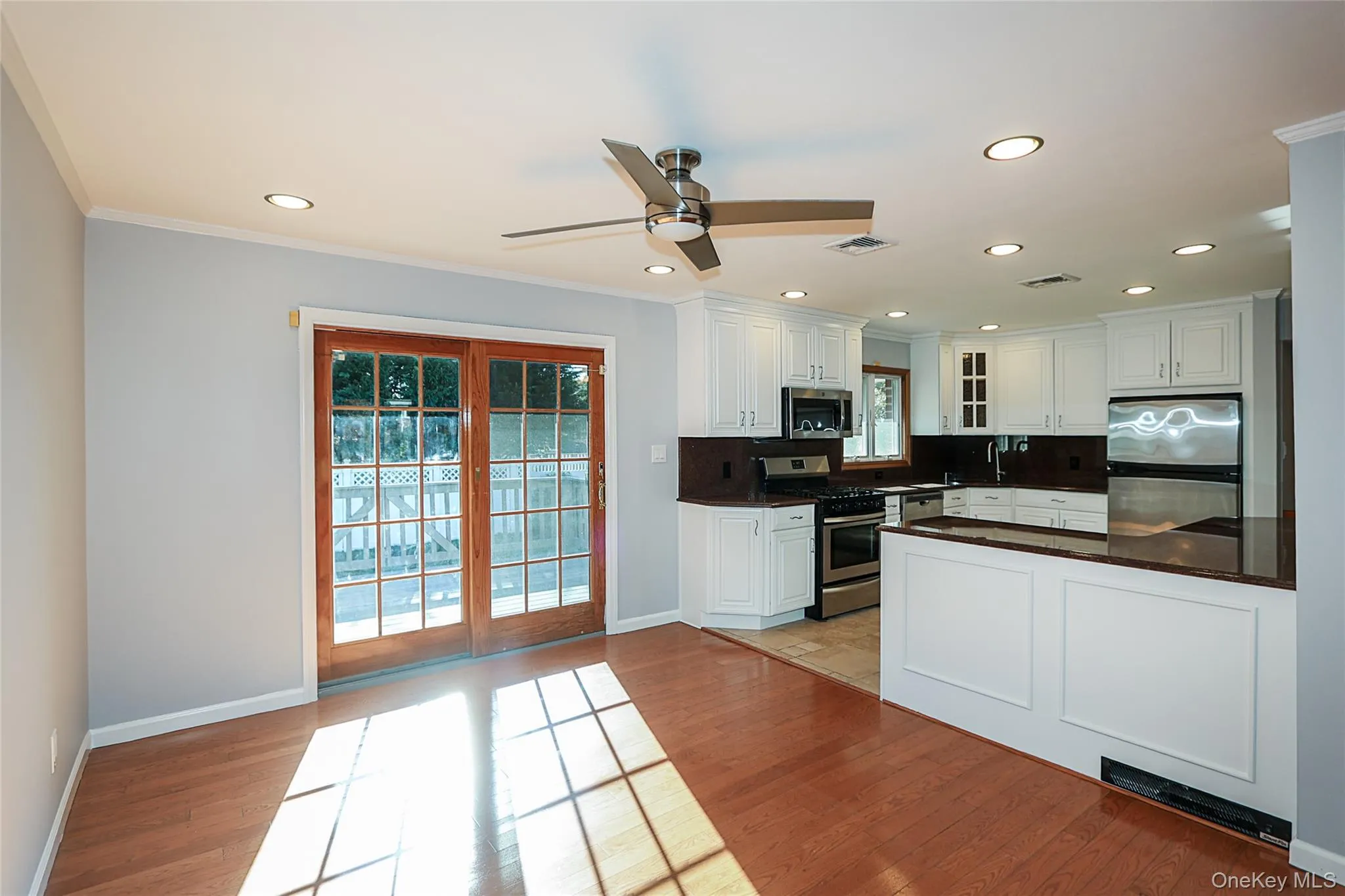Kitchen with stainless steel appliances, white cabinets, a ceiling fan, light wood-style floors, and recessed lighting Kitchen with stainless steel appliances, white cabinets, a ceiling fan, light wood-style floors, and recessed lighting
