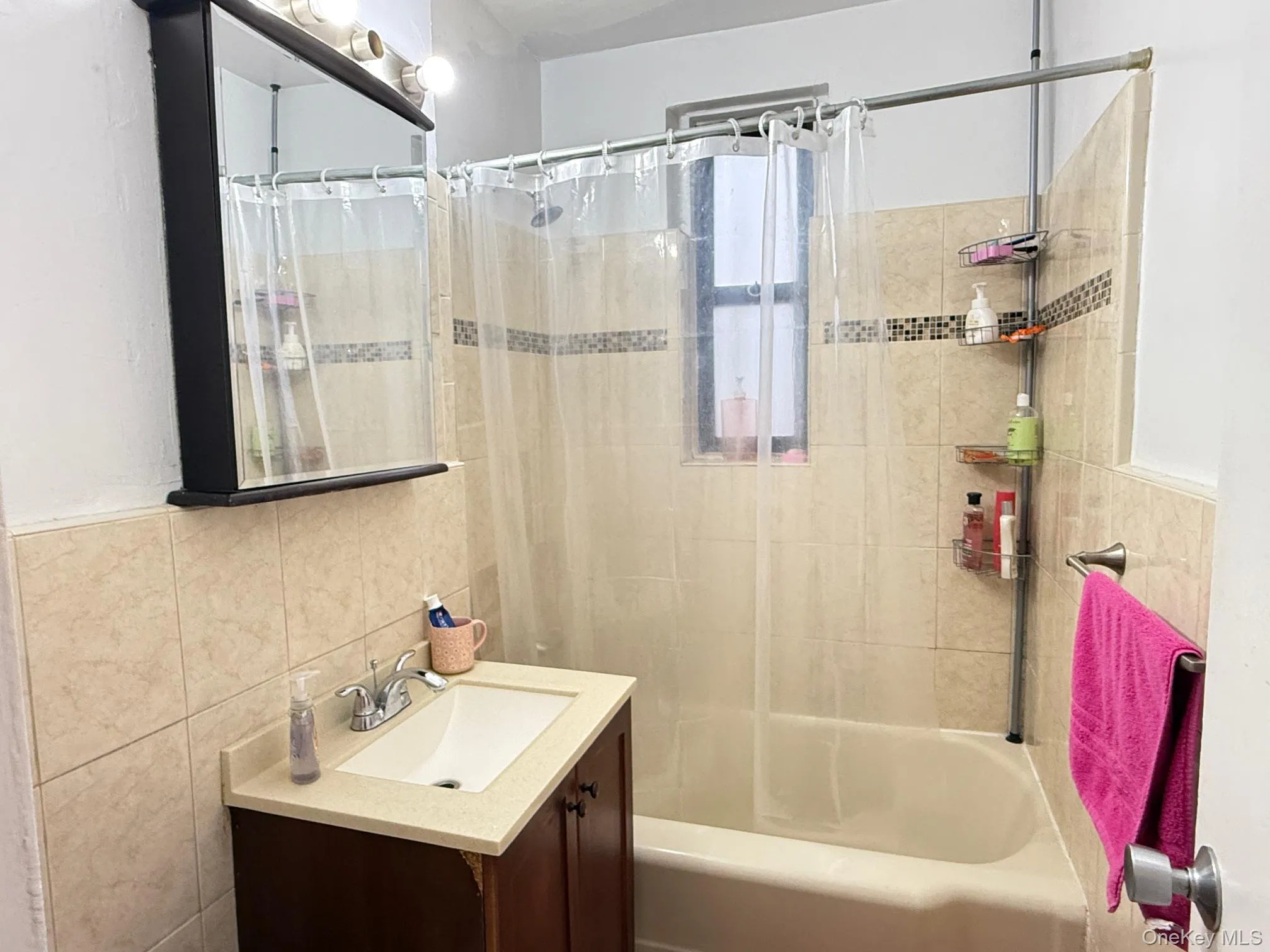 Full bathroom with vanity, shower / bath combo with shower curtain, and tile walls Full bathroom with vanity, shower / bath combo with shower curtain, and tile walls