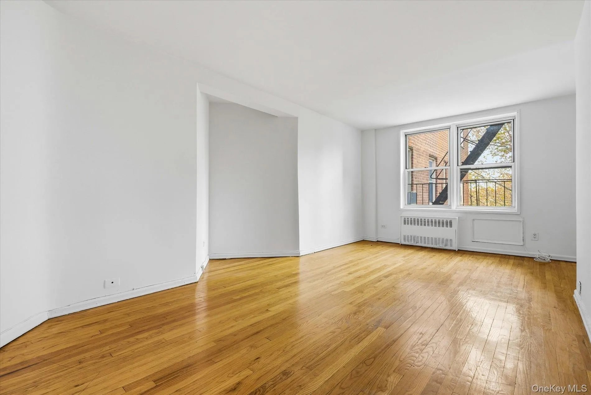 Unfurnished room with light wood finished floors and radiator heating unit Unfurnished room with light wood finished floors and radiator heating unit