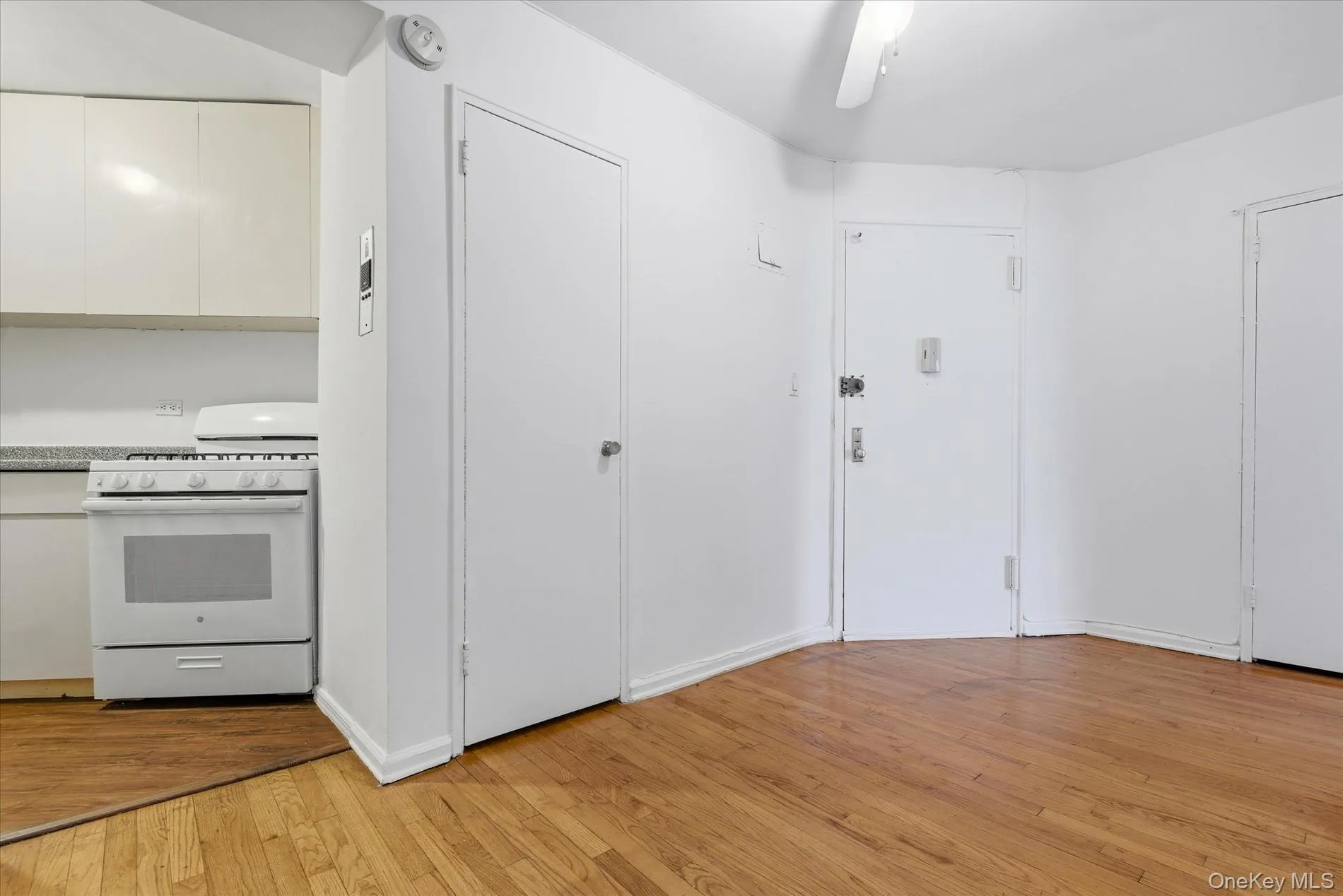 Kitchen with white gas stove, white cabinetry, light wood-style floors, ceiling fan, and modern cabinets Kitchen with white gas stove, white cabinetry, light wood-style floors, ceiling fan, and modern cabinets