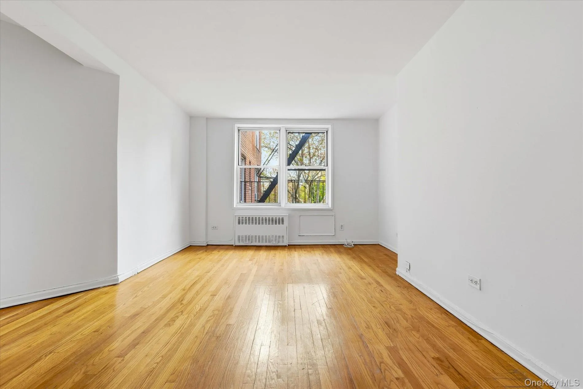 Empty room featuring light wood-style flooring and radiator heating unit Empty room featuring light wood-style flooring and radiator heating unit